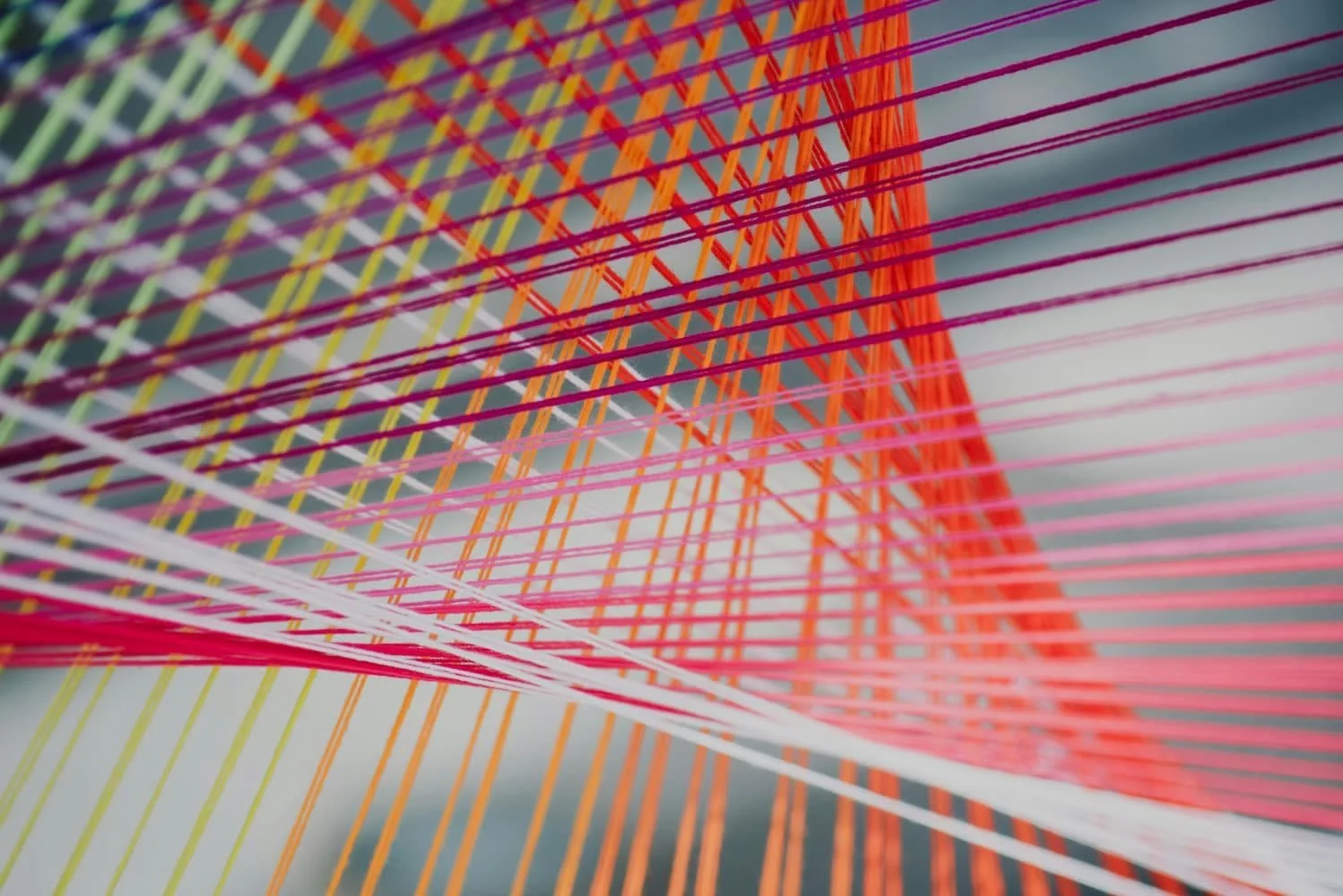 Bunte Fäden, die ineinander laufen und ein Netz aus Linien und Knotenpunkten ergeben.