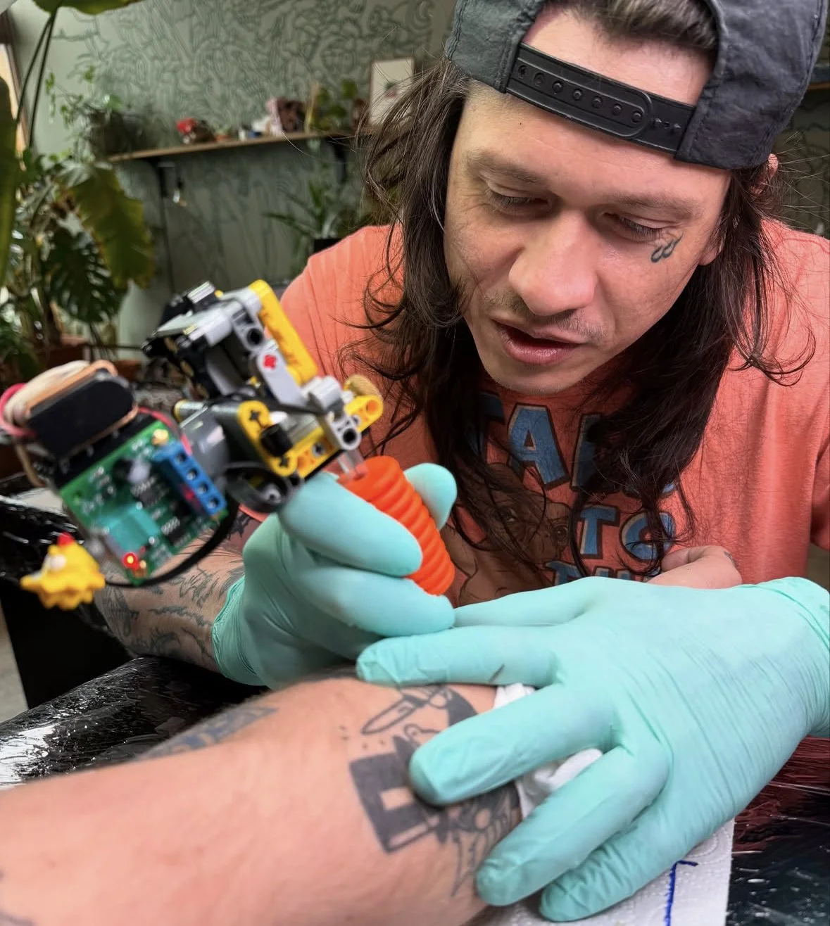 Tattoo artist using a robotic arm to tattoo a person's forearm.