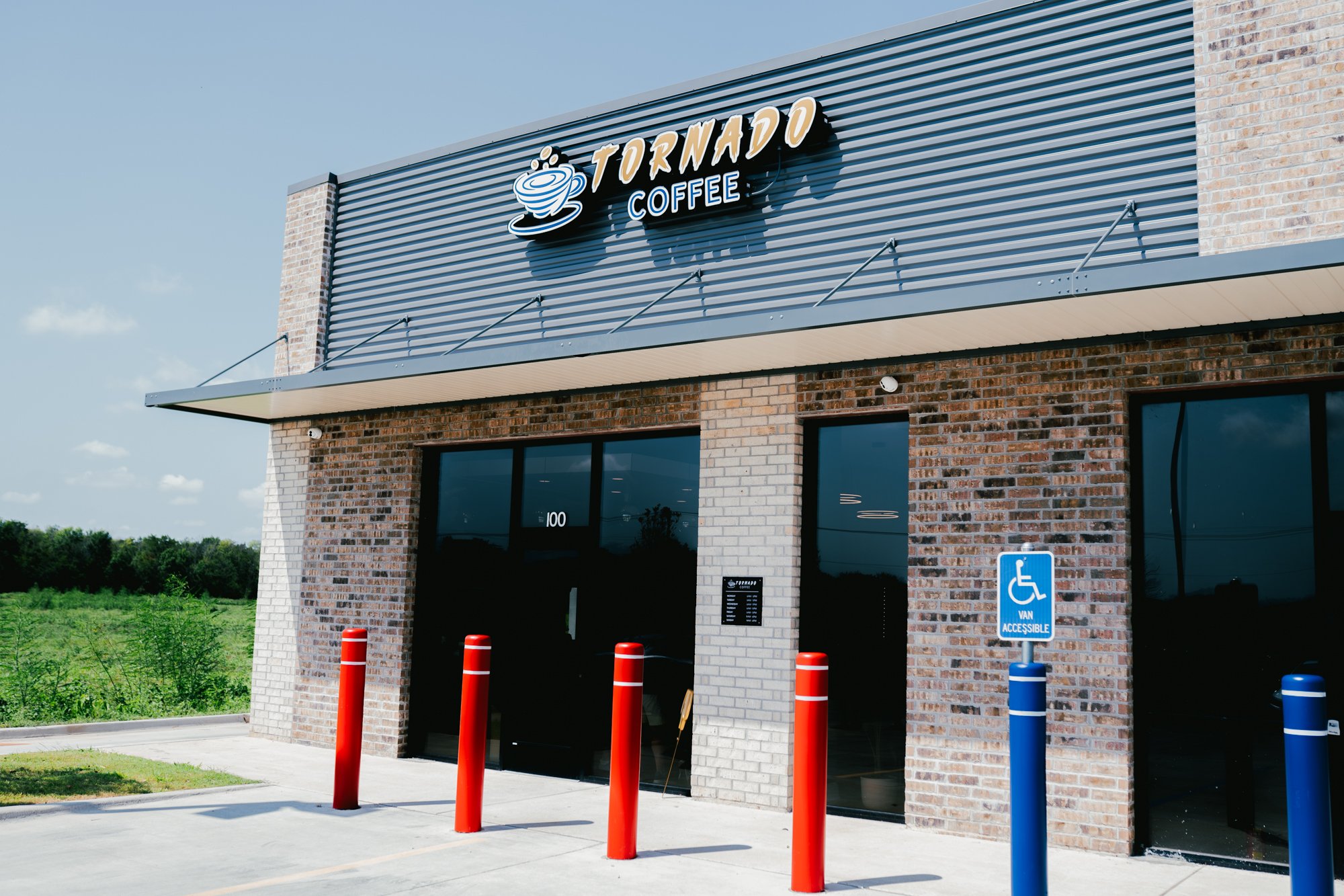 Exterior of a Starbucks coffee shop with a brick facade, with a sign reading "Tornado Coffee" featuring a coffee cup icon, and a wheelchair accessible parking sign in the foreground.