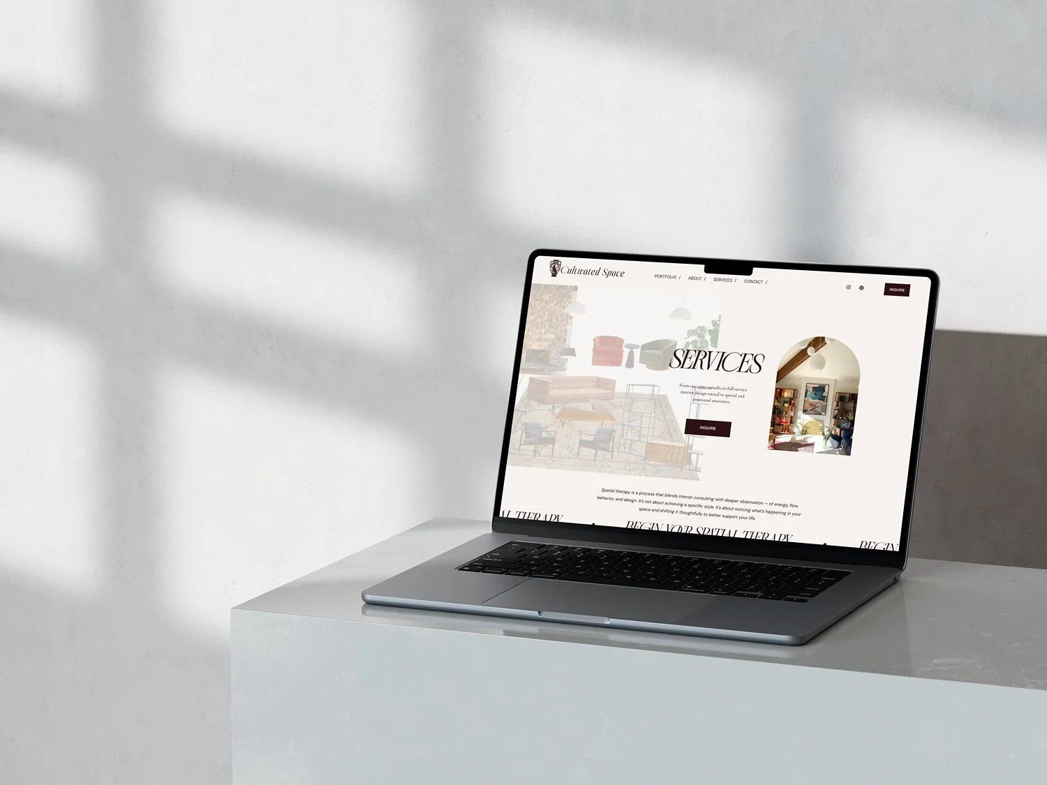 Laptop on white table displaying a website about interior design services.