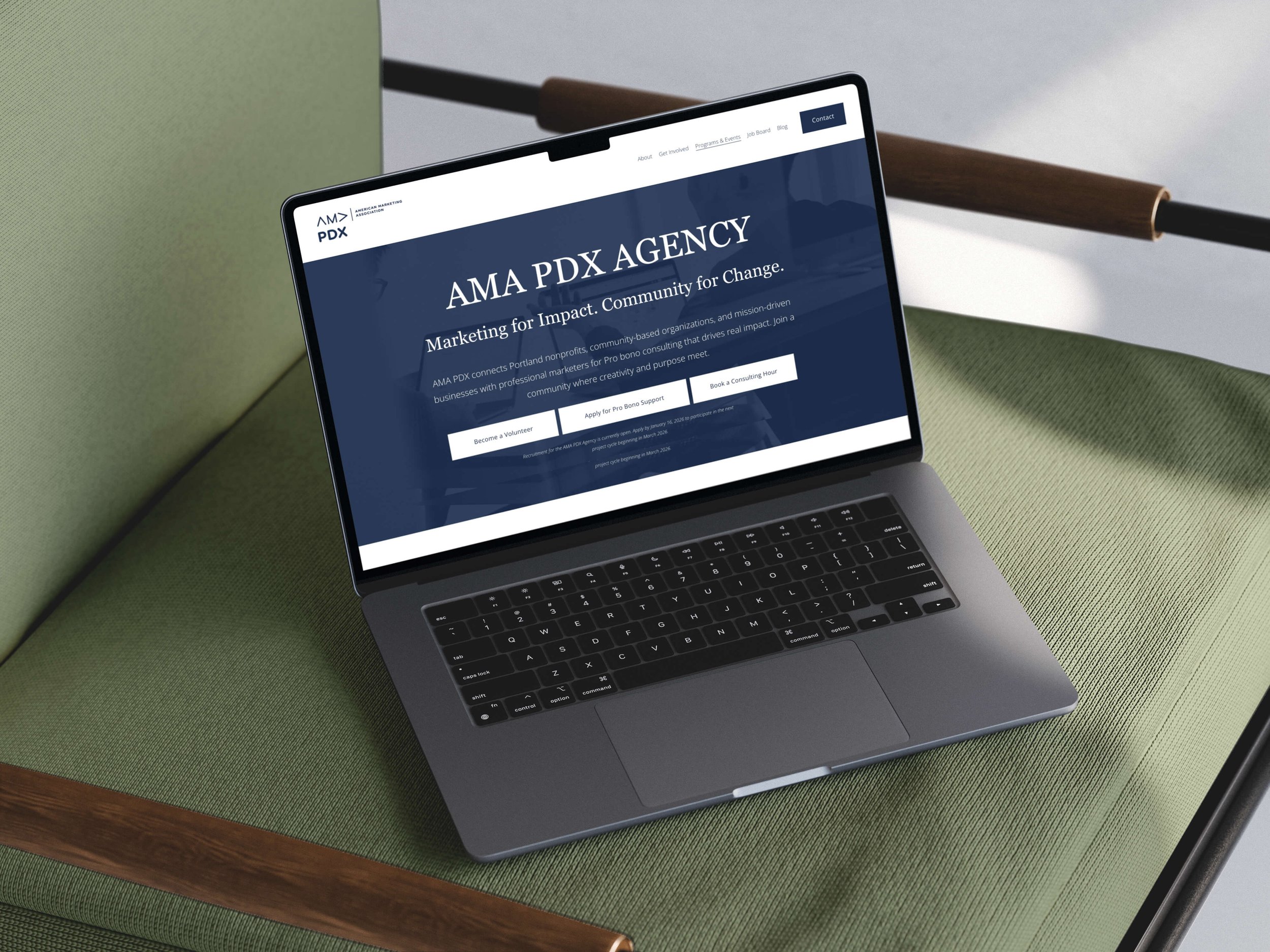 A laptop open on a green chair with a website for AMA PDX Agency displayed on the screen.