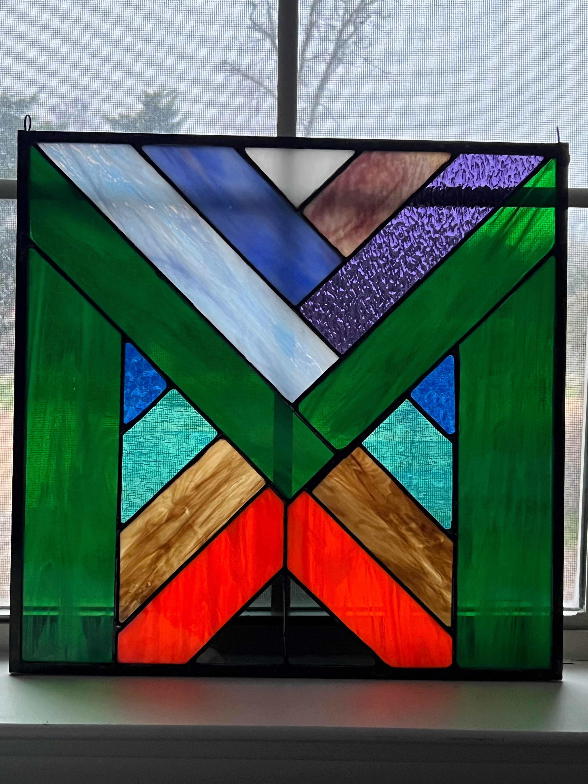 MEarth started as a design for an "M" person who loved the color green. As I began selecting just the right glass though, I began to see the piece in a different light. At the bottom center is the black iron core of the earth, then a layer of molte