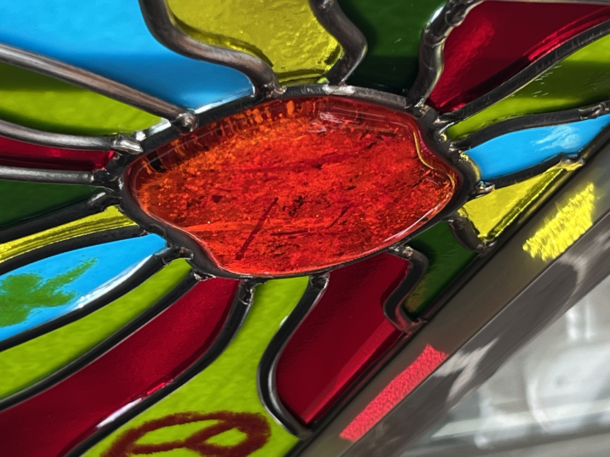 This view of "Psychedelic Sunset" highlights the complex interplay among the 9 mm center orb, the thinner 3 mm rays and heaviness of the lead came, all combining to give it a definite early-70s look. 12" x 12" with 5/32" lead came and frame.