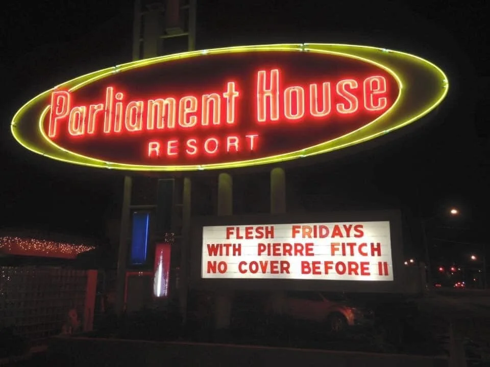 The Parliament House Resort neon sign and billboard underneath that reads "FLESH FRIDAYS WITH PIERRE FITCH NO COVER BEFORE 11"