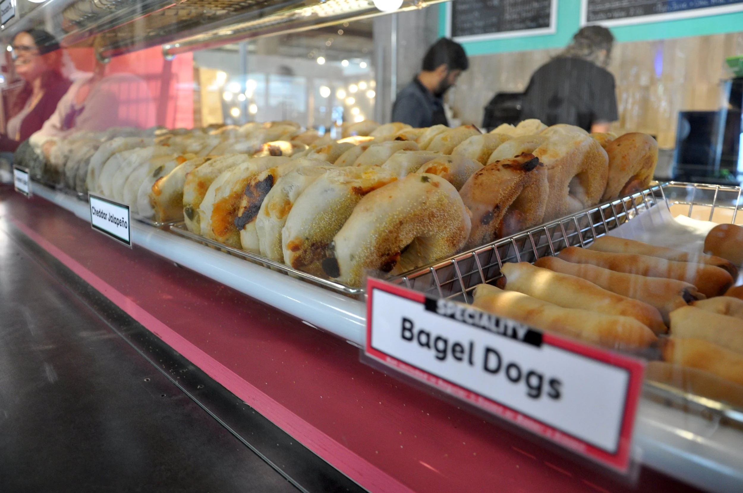 The Dough Bagel Co display case at their Goods & Co. location feautring cheddar jalapeno bagels and their bagel hot dogs