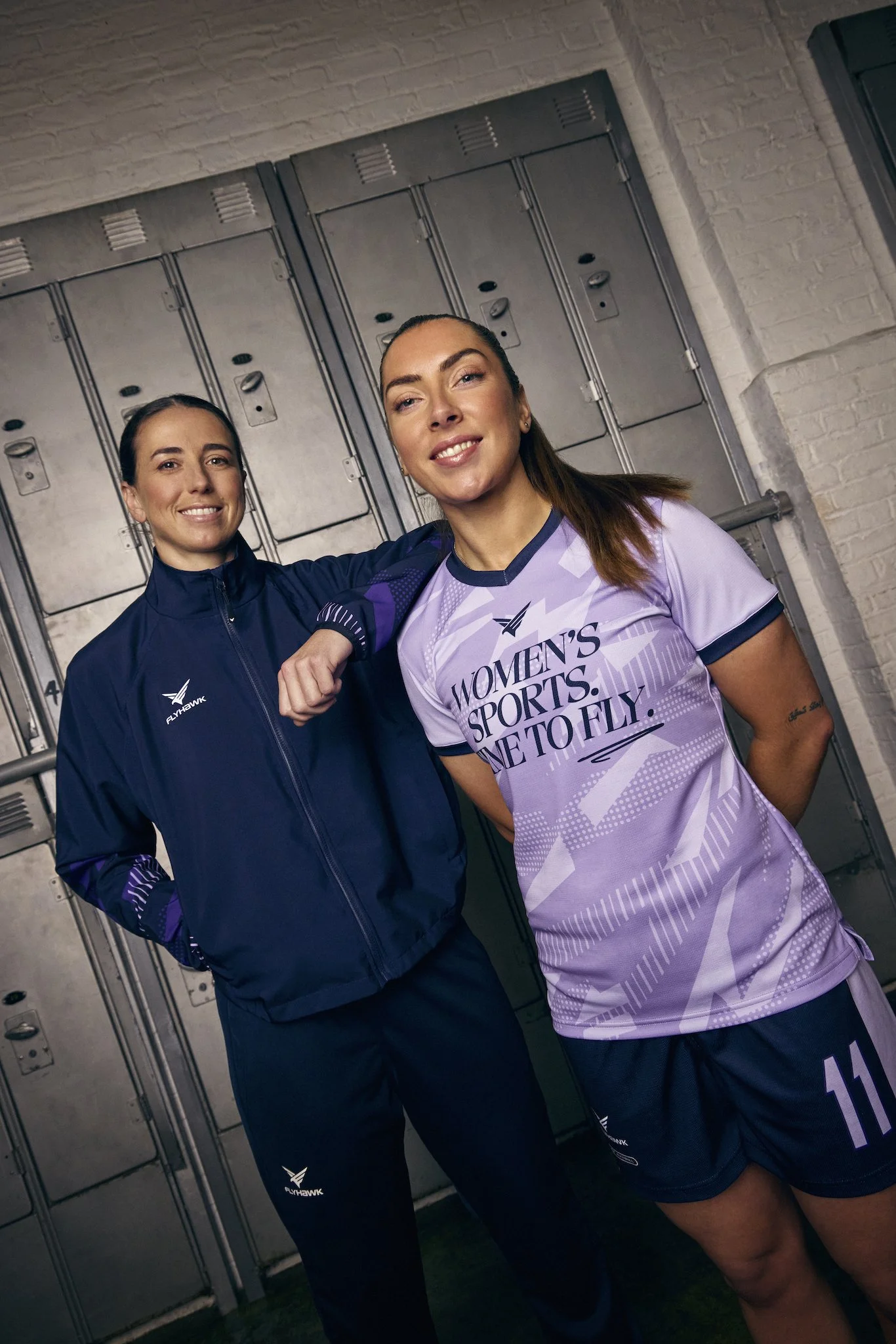 Two women in athletic attire standing in front of lockers in a sports facility.
