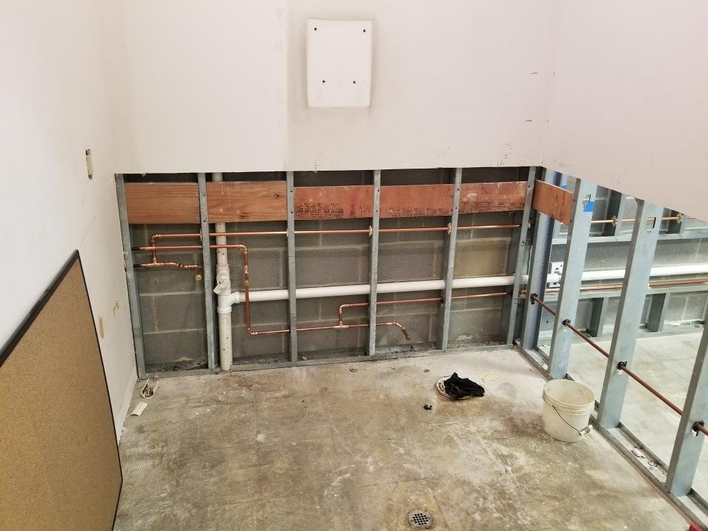 Intricate installation of copper water lines and PVC waste lines within the walls of a new construction job site, demonstrating precision plumbing craftsmanship