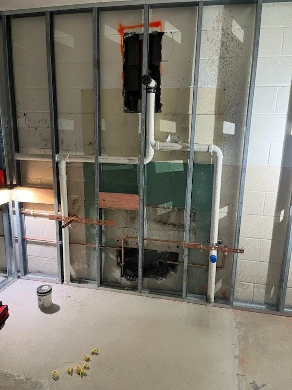 commercial bathroom plumbing rough in showing professionally installed copper water and pvc waste lines