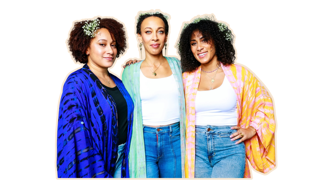 Three women with curly hair standing close together, smiling, against a plain white background.