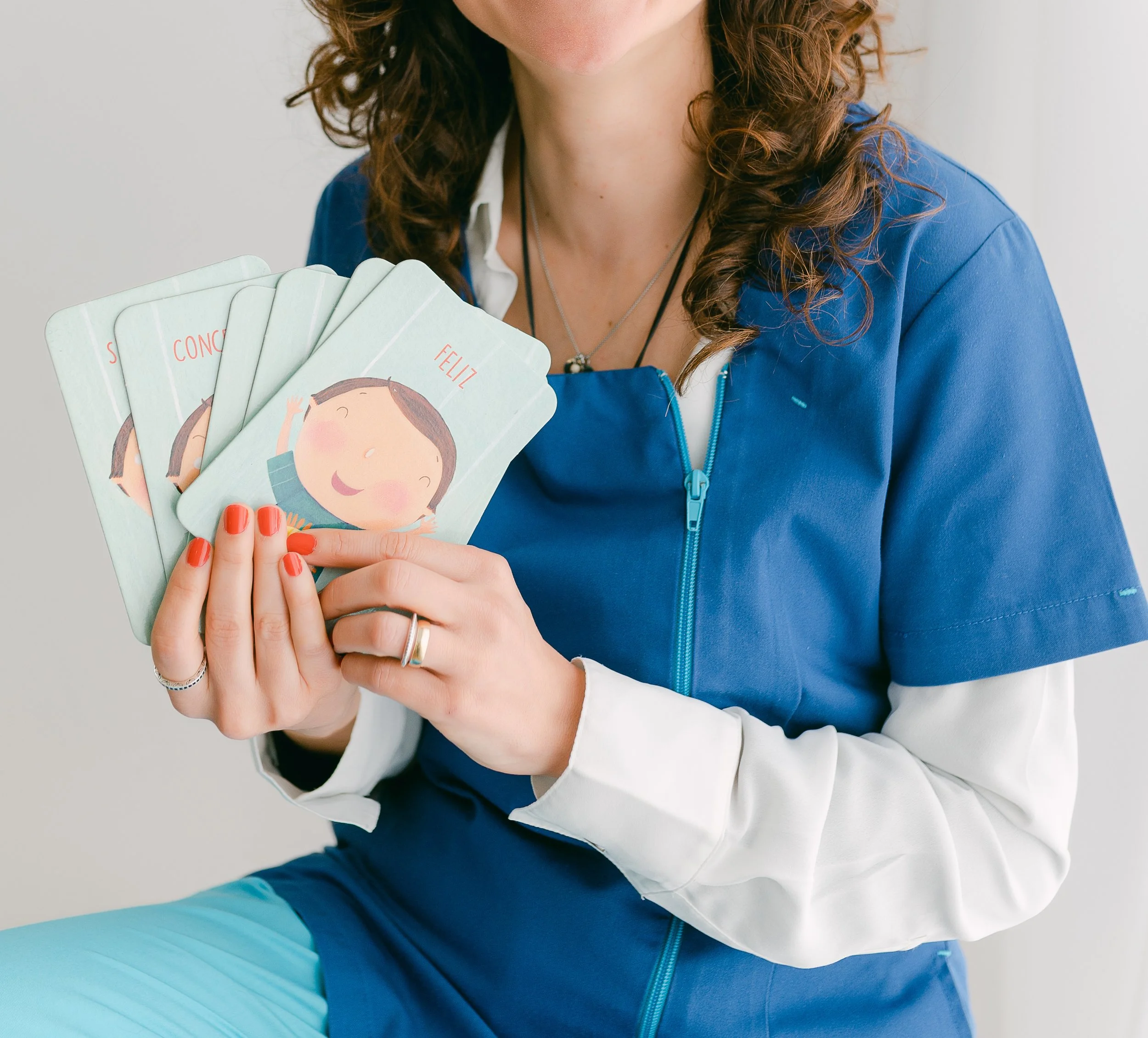 Terapeuta a segurar cartas com ilustrações de expressões faciais.