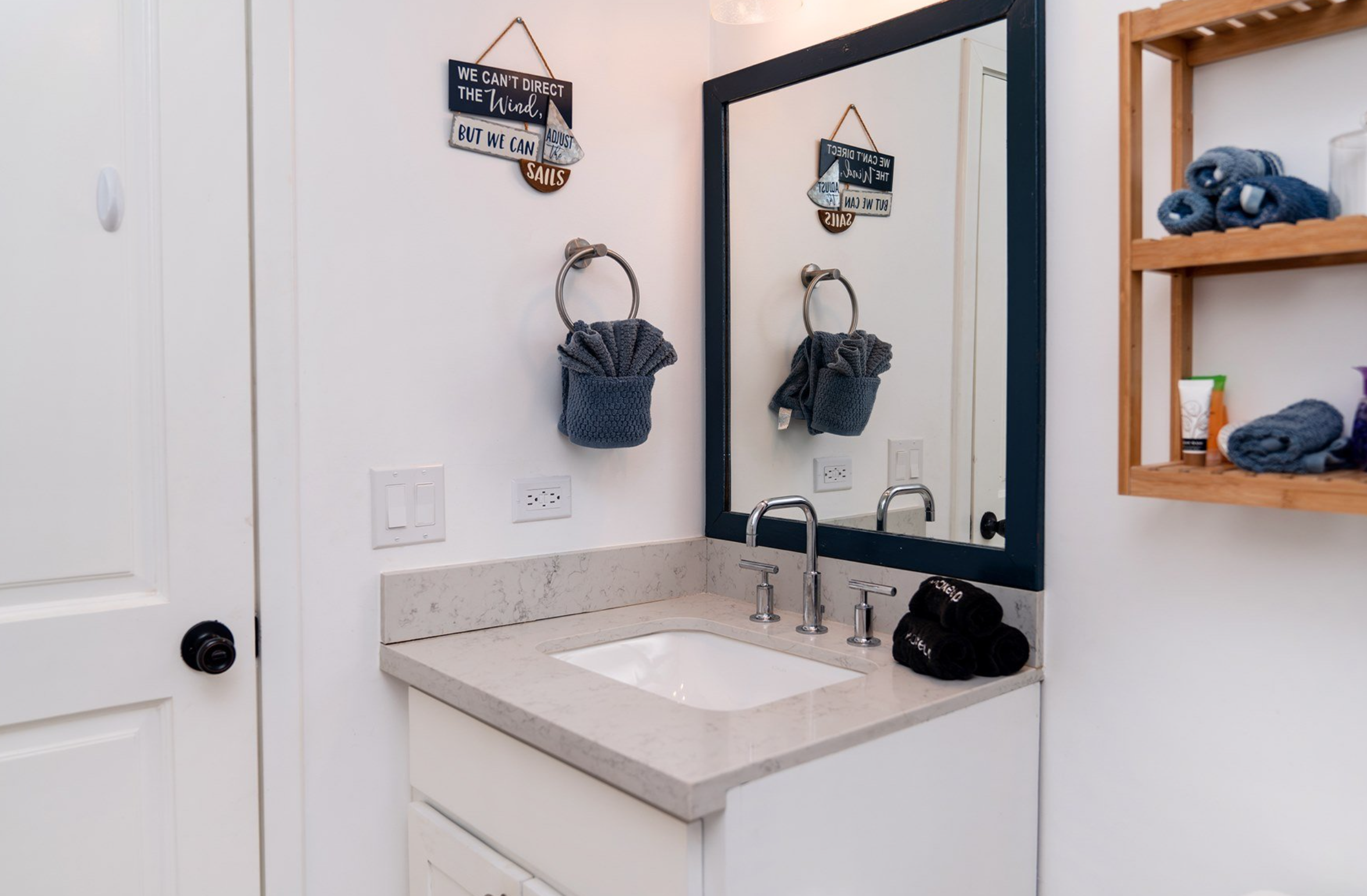 Bathroom with a sink, mirror, towel, wall art, and shelving.