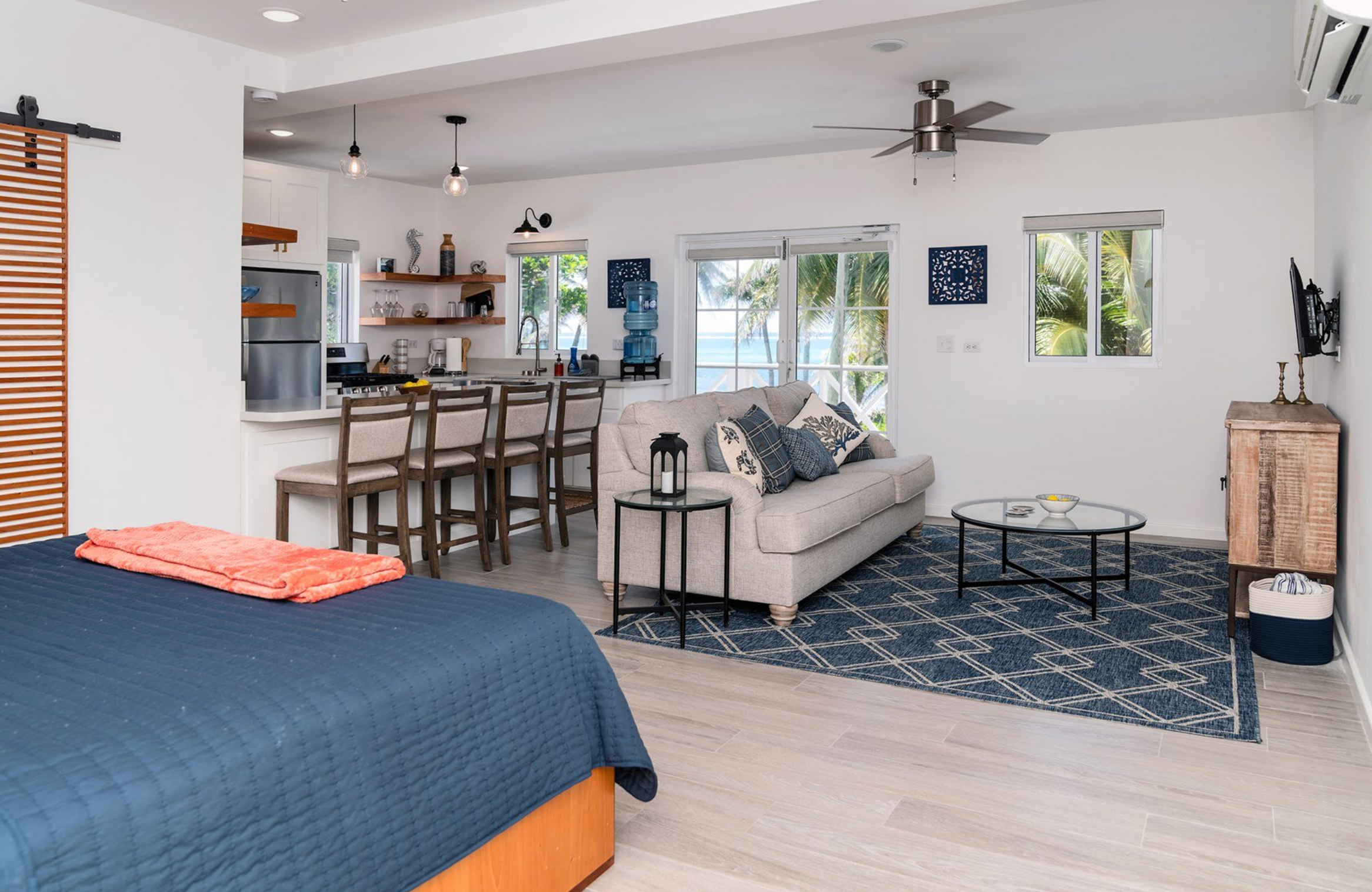 Open-concept living area with a bed, couch, kitchen, and ocean view.