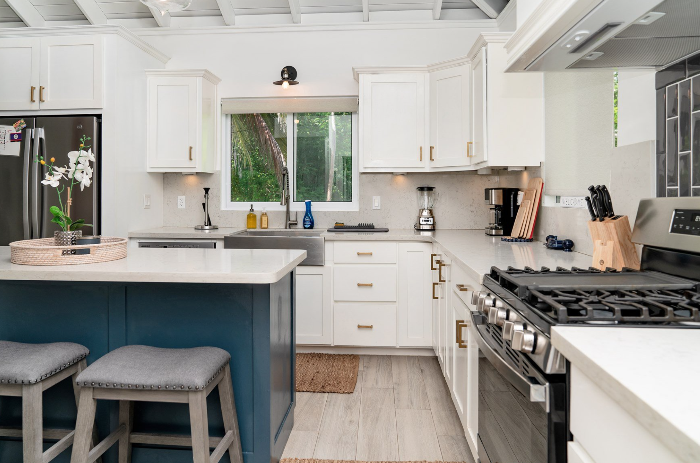 Modern kitchen with white cabinets, stainless steel appliances, blue island, and neutral decor.