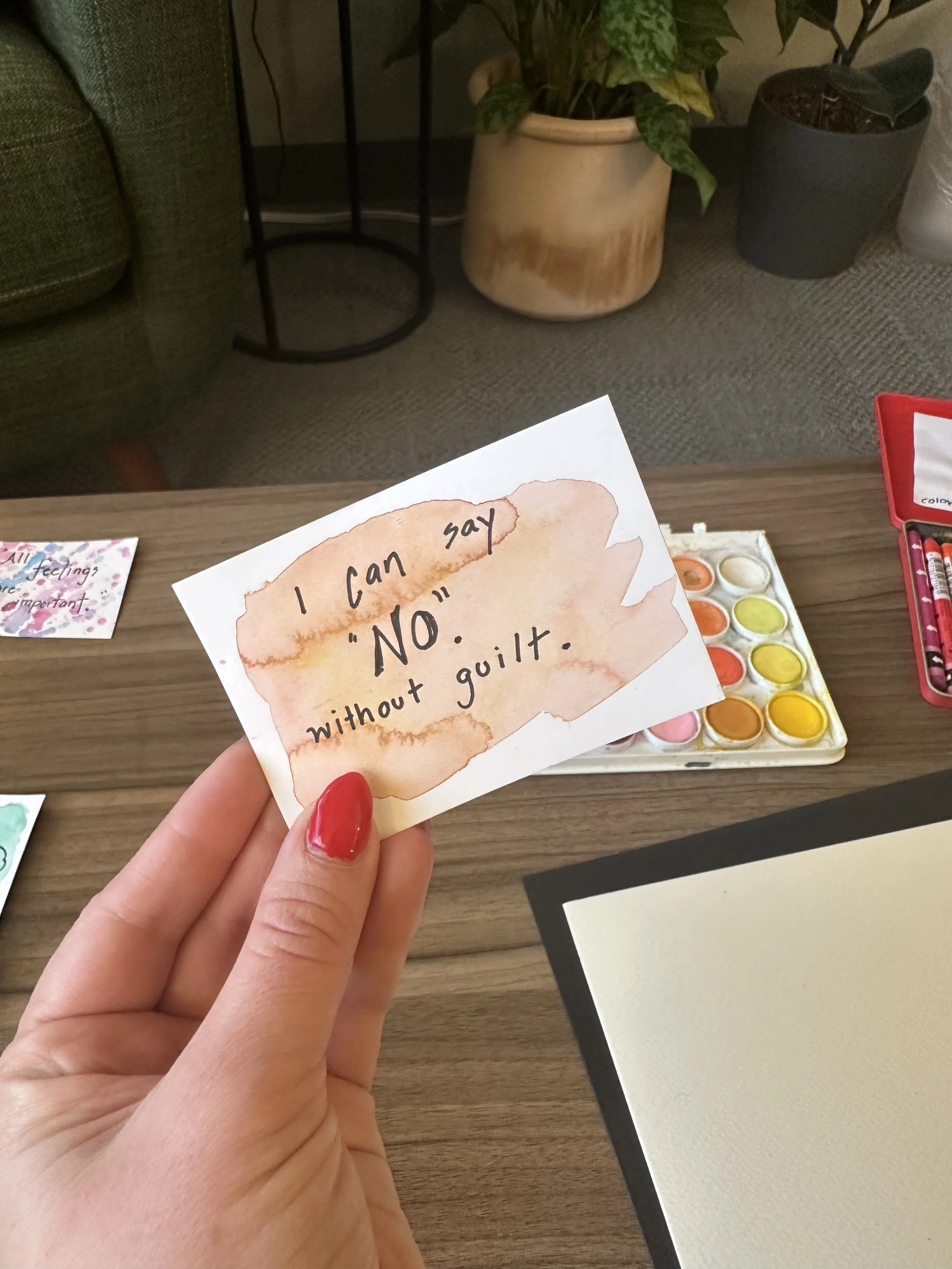 Hand holding an affirmation card stating "I can say "no" without guilt.