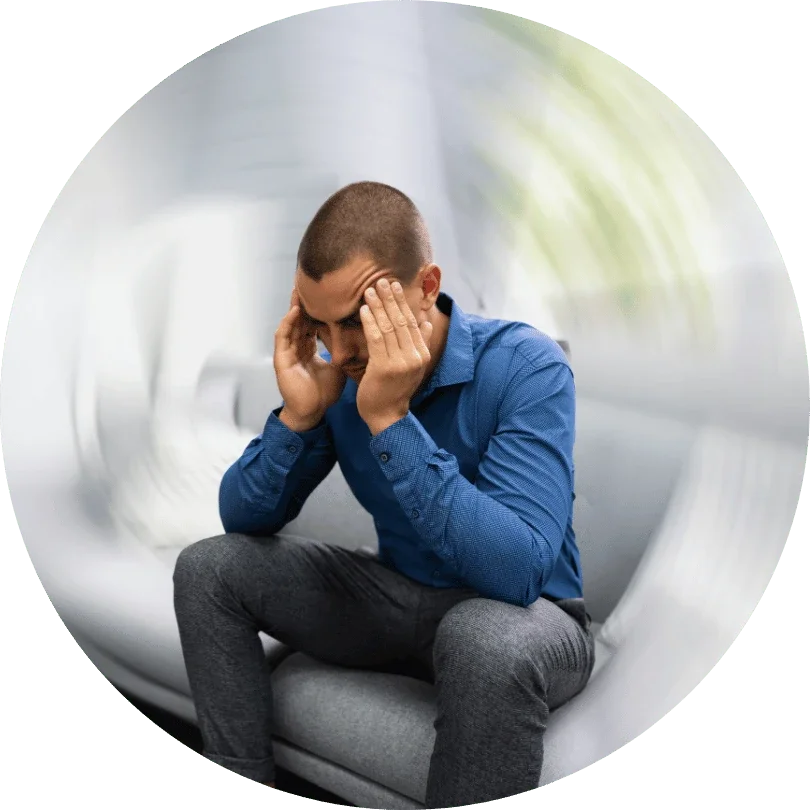 Man sat down in white couch with hands on his head due to dizziness