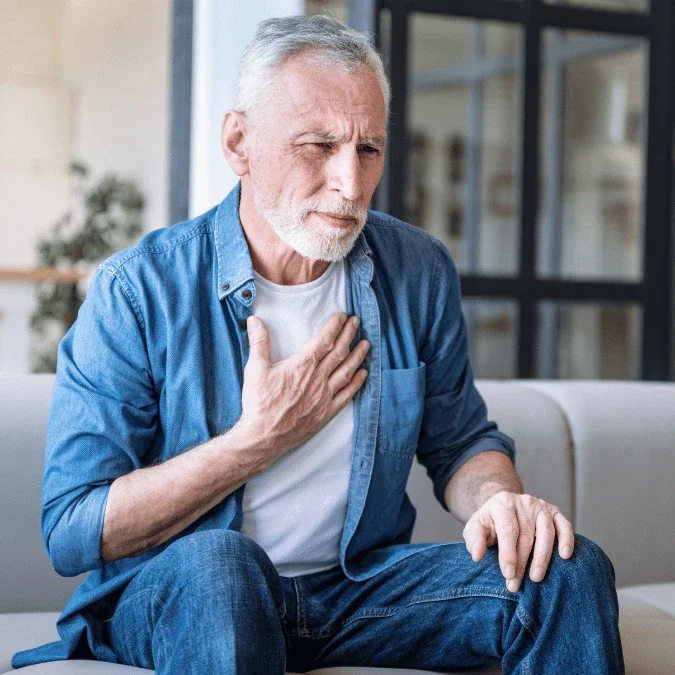 elderly man feeling his chest as he experience tachycardia caused by dysautonomia