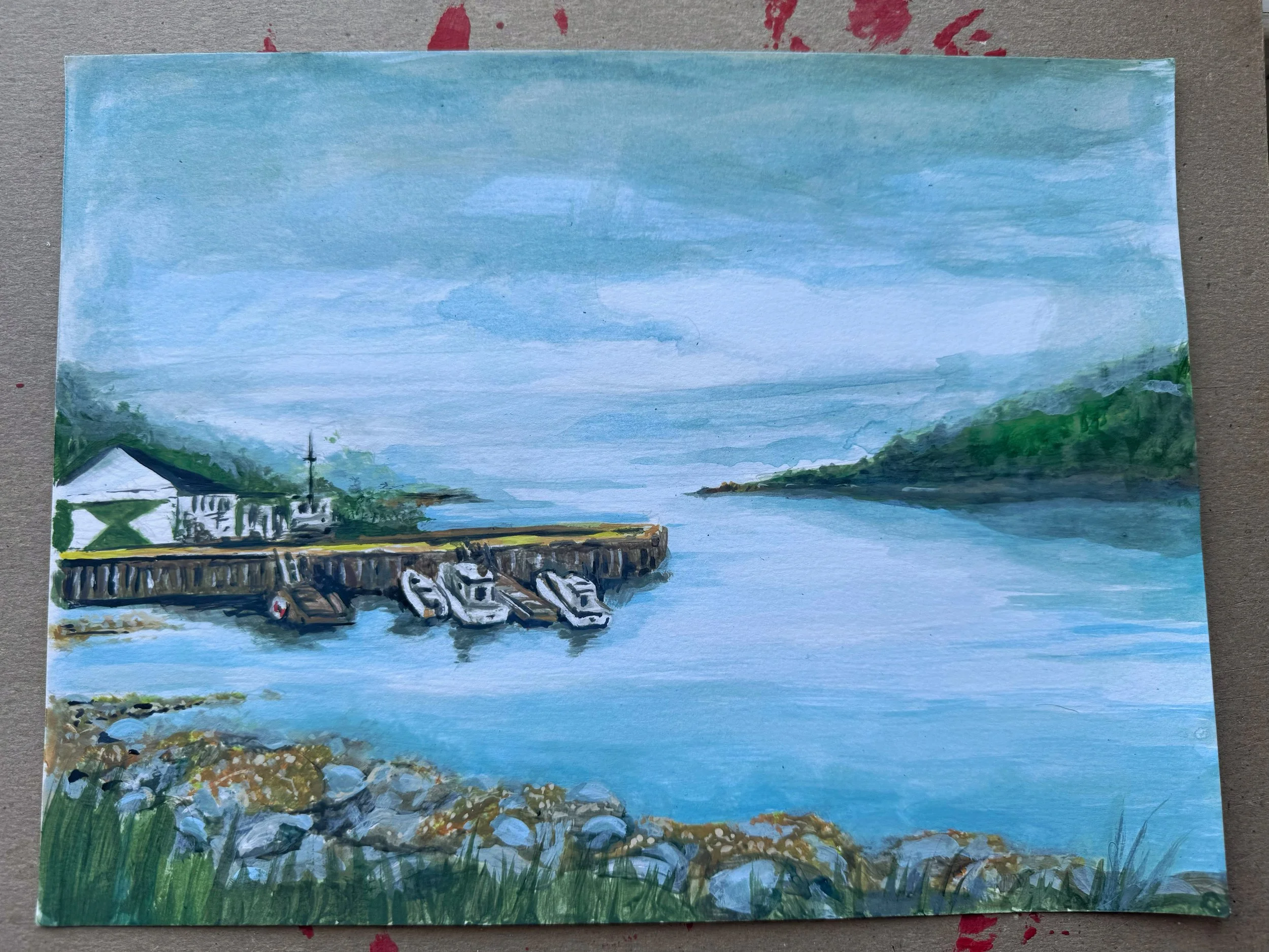 A painting of a small harbor with four boats docked, a white building with a black roof, green trees, and a cloudy sky over calm water, with hills in the background.