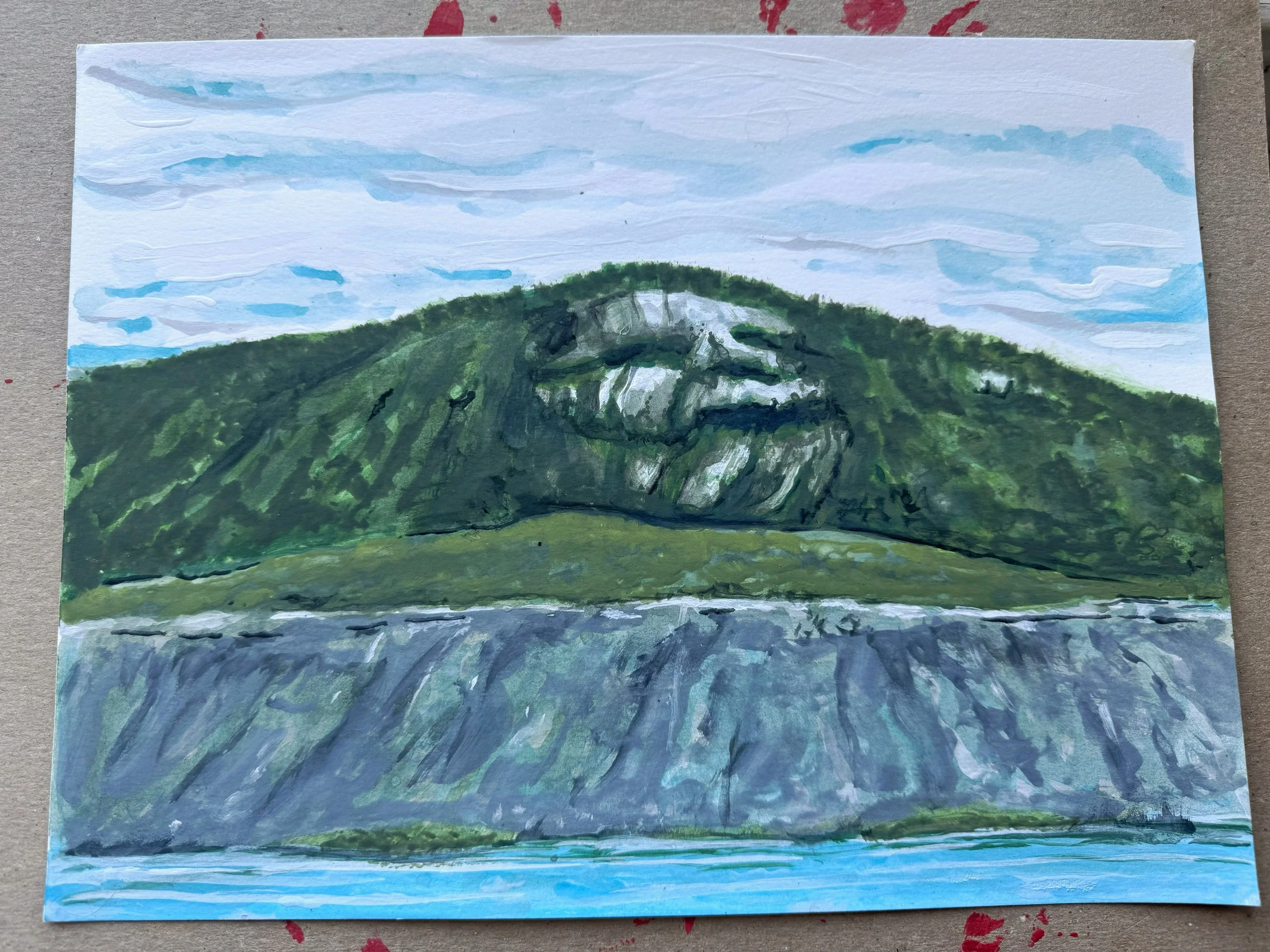 A watercolor painting of a green, mountainous landscape with a body of water in the foreground and a partly cloudy sky above.