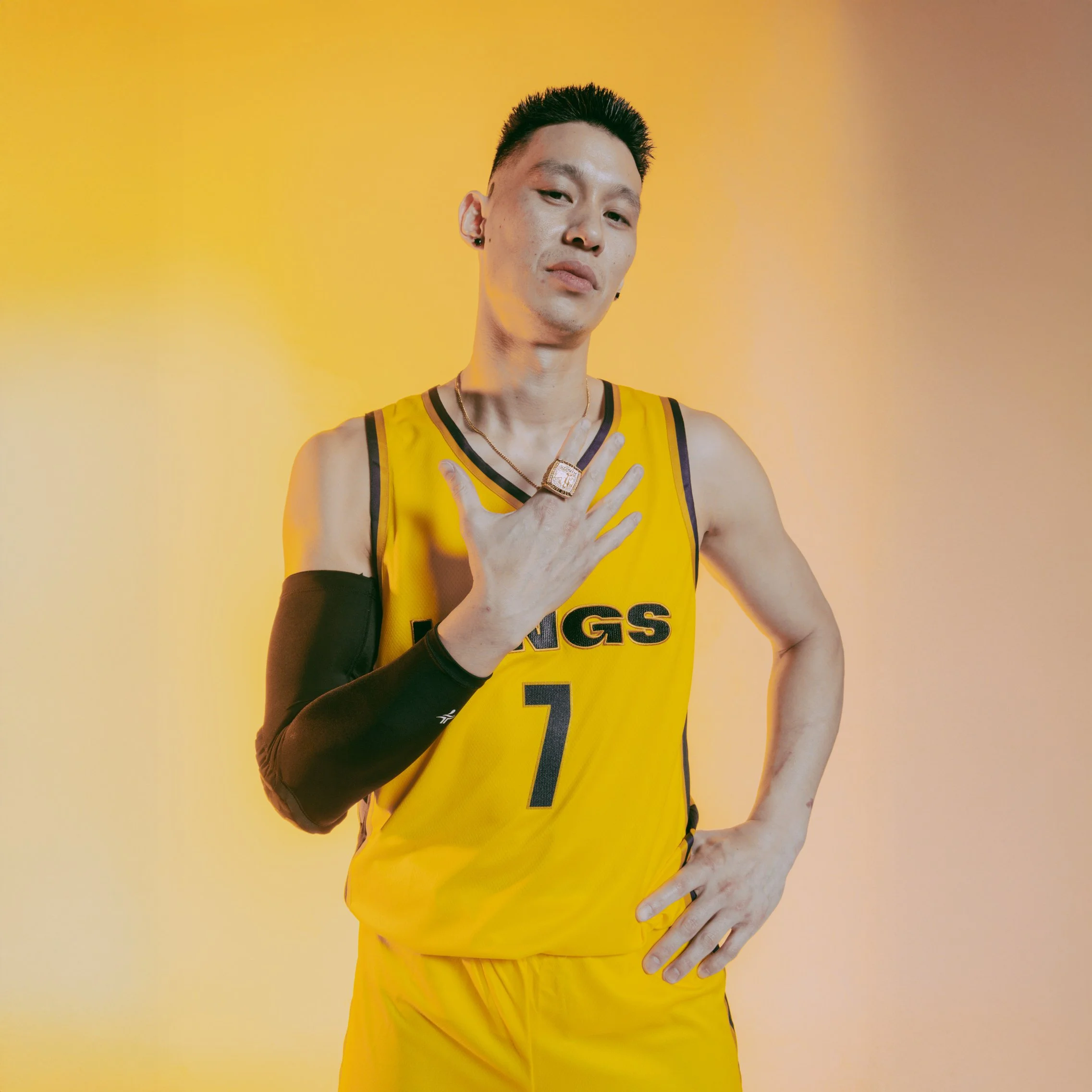 A person in a yellow basketball jersey with the number 7, posing with one hand on their hip and the other hand near their chest, against a yellow background.