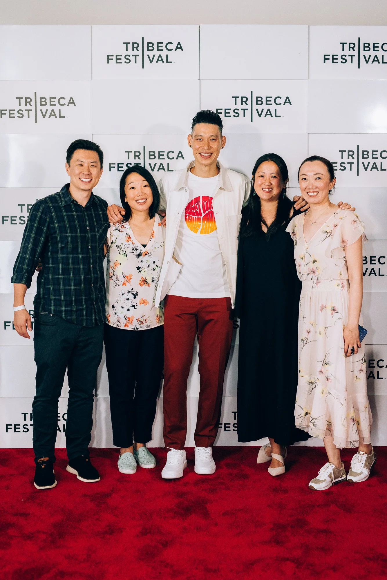 Group of five people standing on a red carpet at Tribeca Film Festival, smiling, with a background displaying the event's logos.