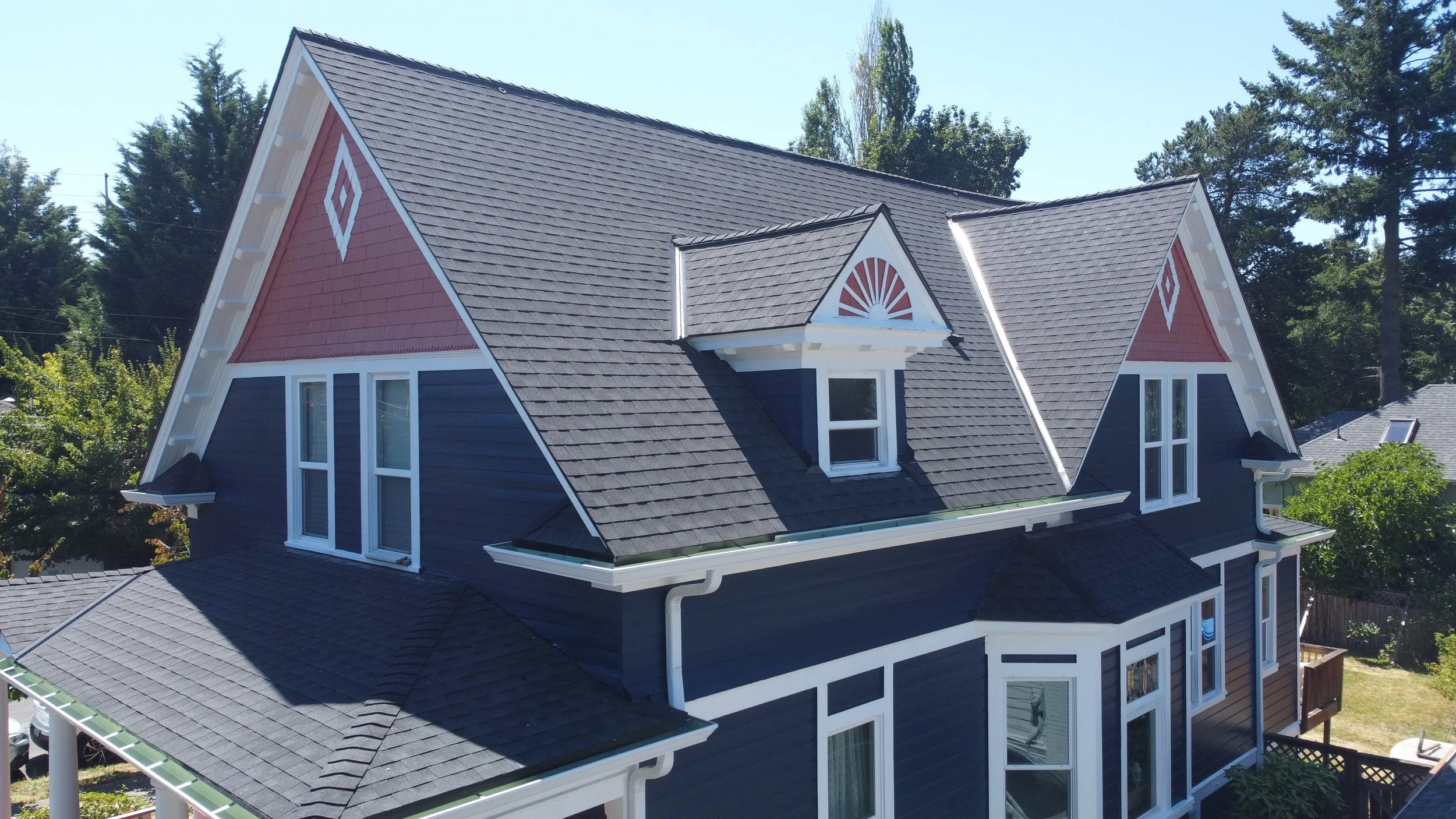 A large, multi-story house with fresh painted exterior siding and a new roof installation by AE&I Roofing and Construction
