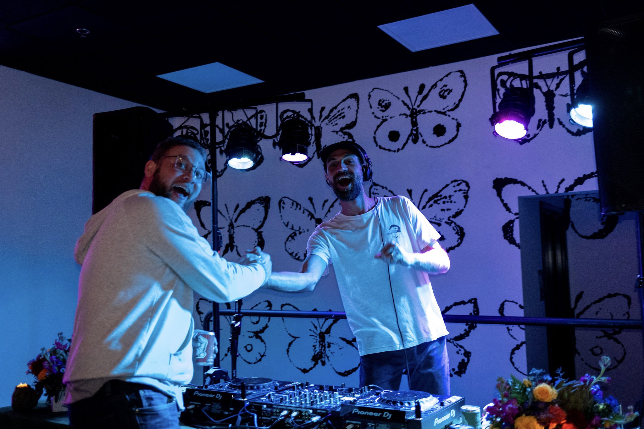 DJ and fan shake hands and smile for the camera at the DJ booth