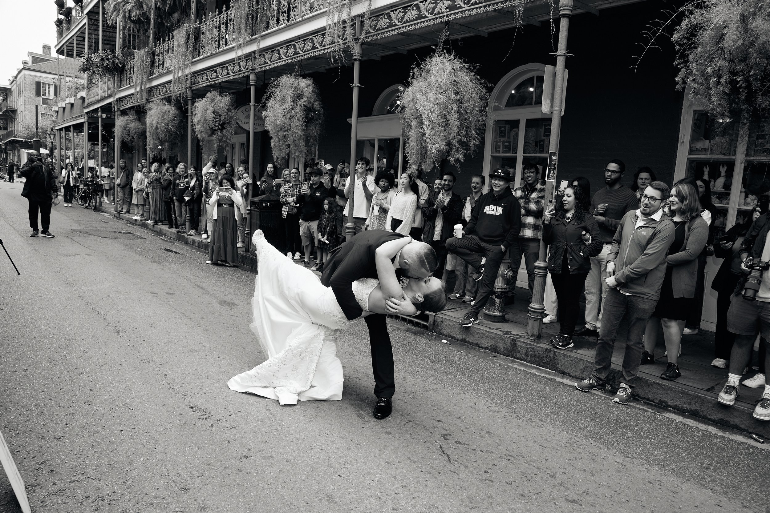 groom once again dips his bride in front of tourist visiting nola's french quarter