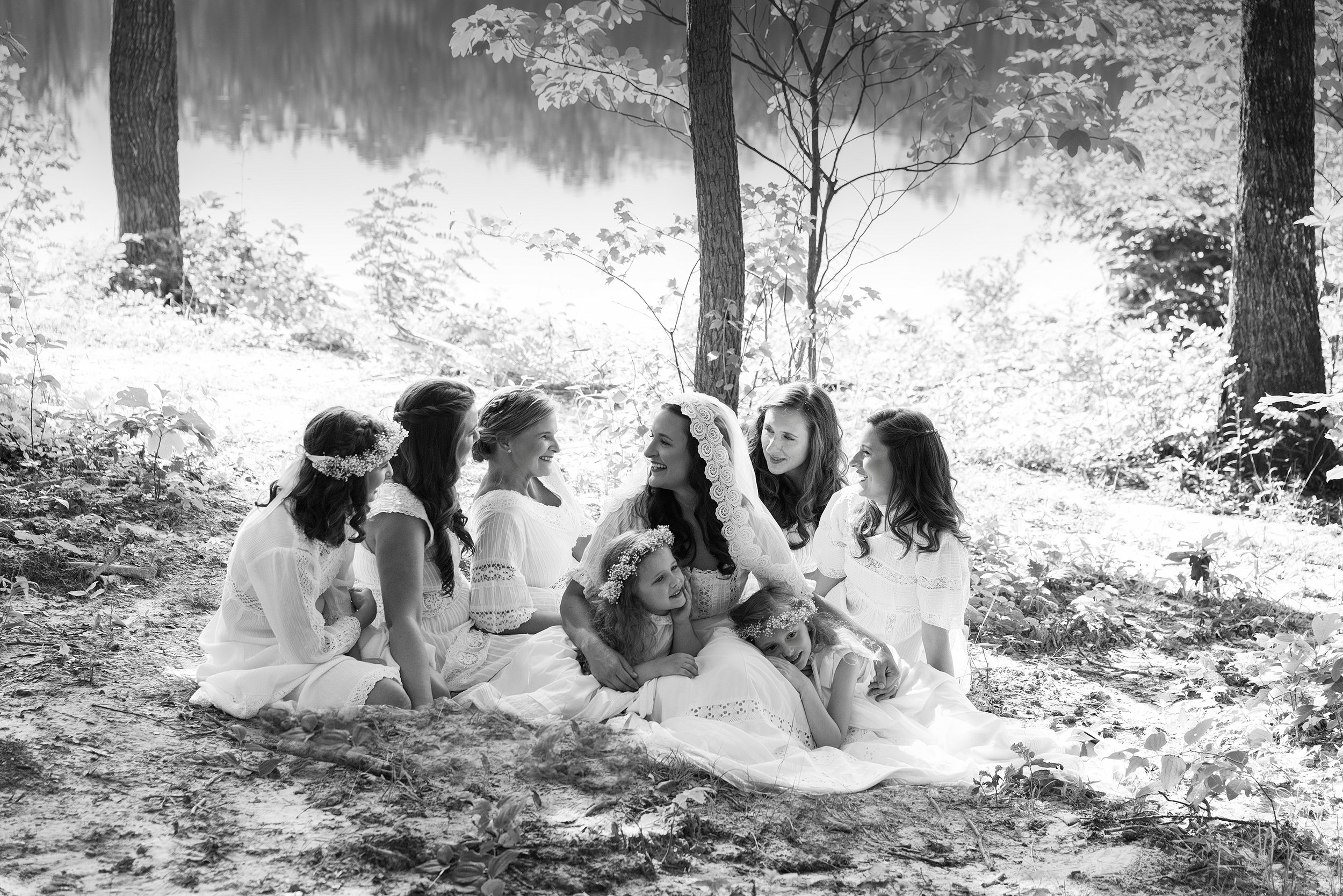 a group of ethereally dressed bride and bridesmaids on a blanket in the forsest