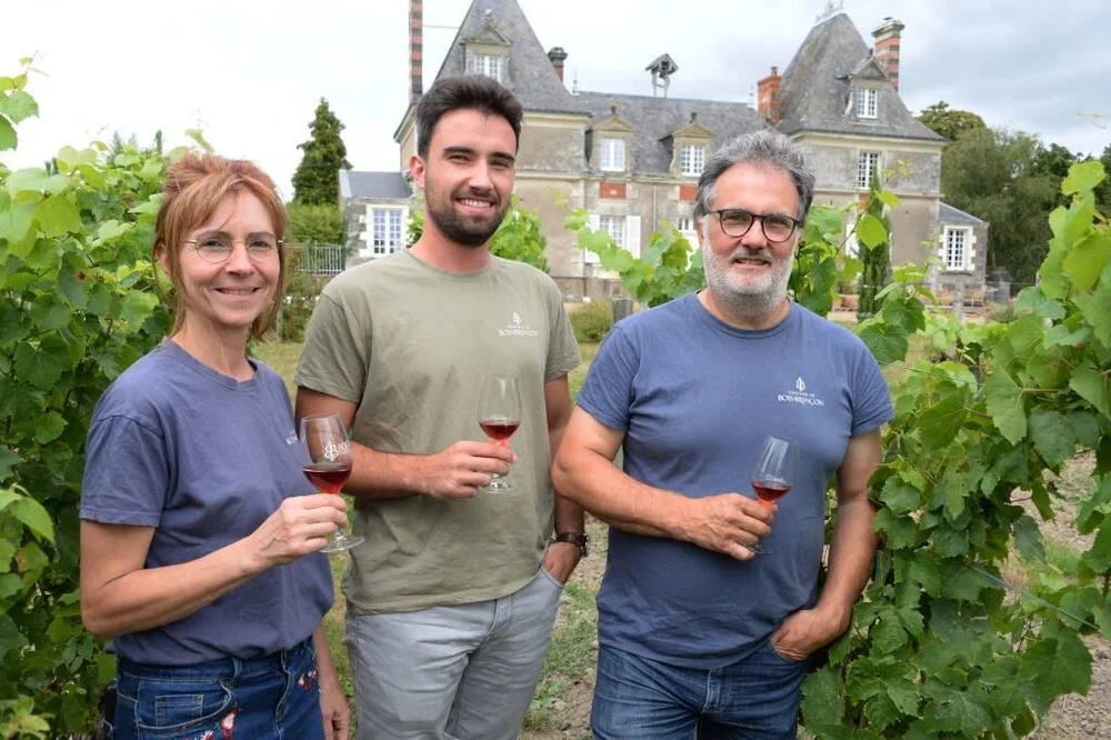 Trois personnes dans les vignes devant le château