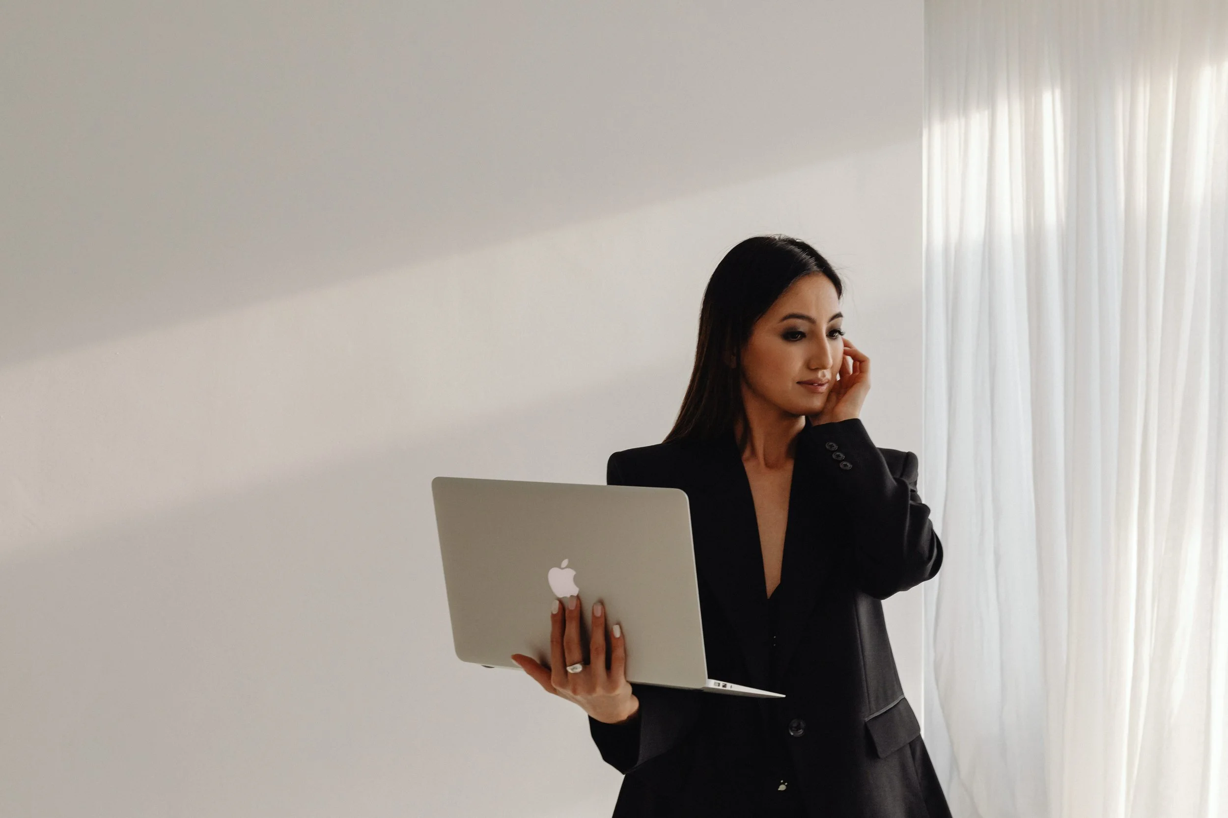 Business owner holding a laptop while planning work, illustrating the importance of choosing one primary AI instead of managing multiple disconnected tools.