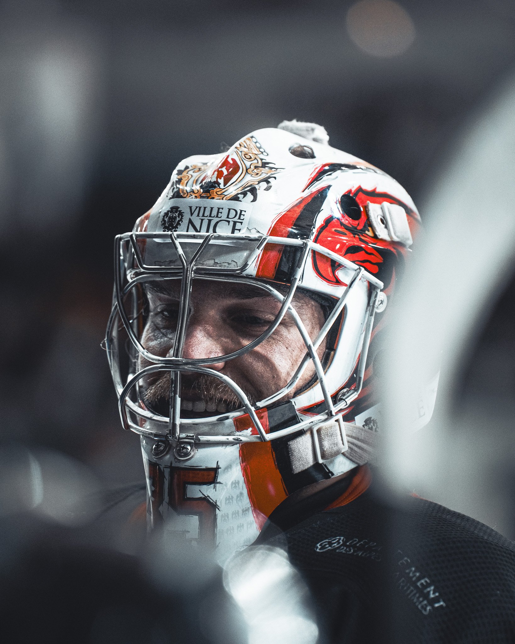 Un gardien de hockey portant un casque décoré avec l'inscription 'Ville de Nice' en jeu.