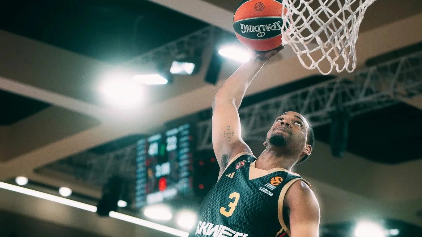 Un joueur de basketball en train de sauter pour dunker le ballon dans le panier.