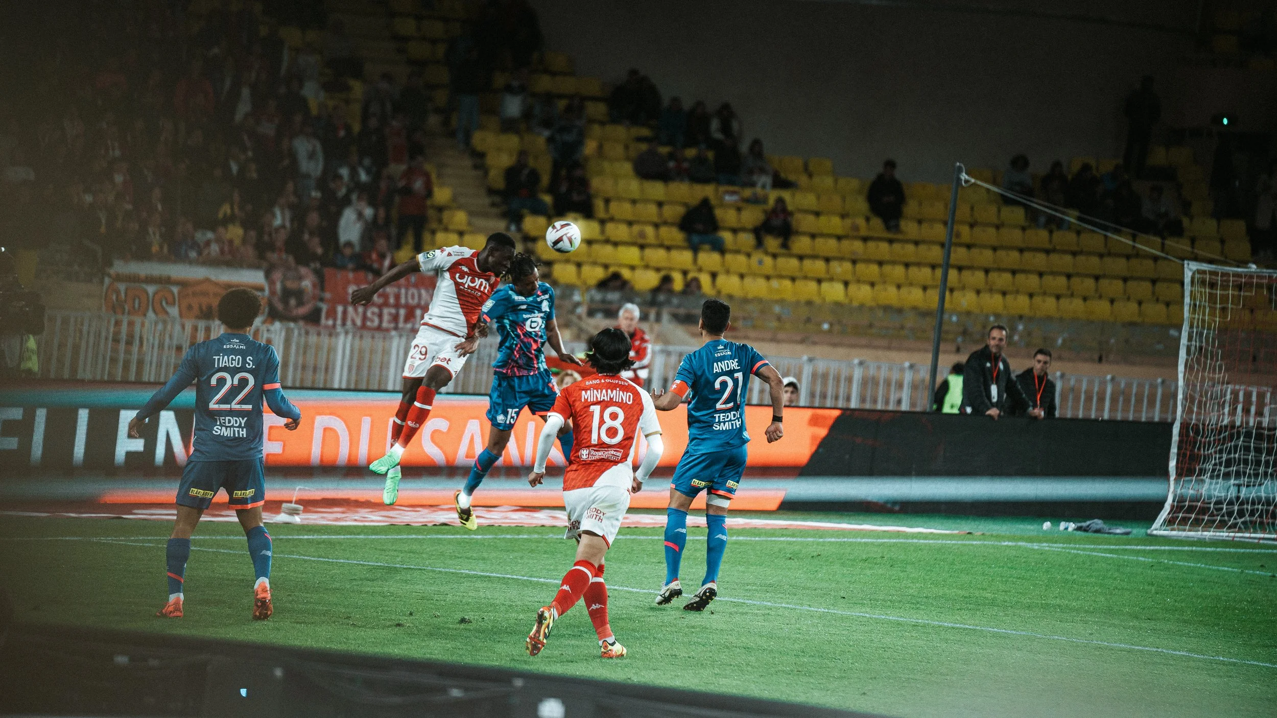 Joueurs de football pendant un match, l'un sautant pour une tête près du but.