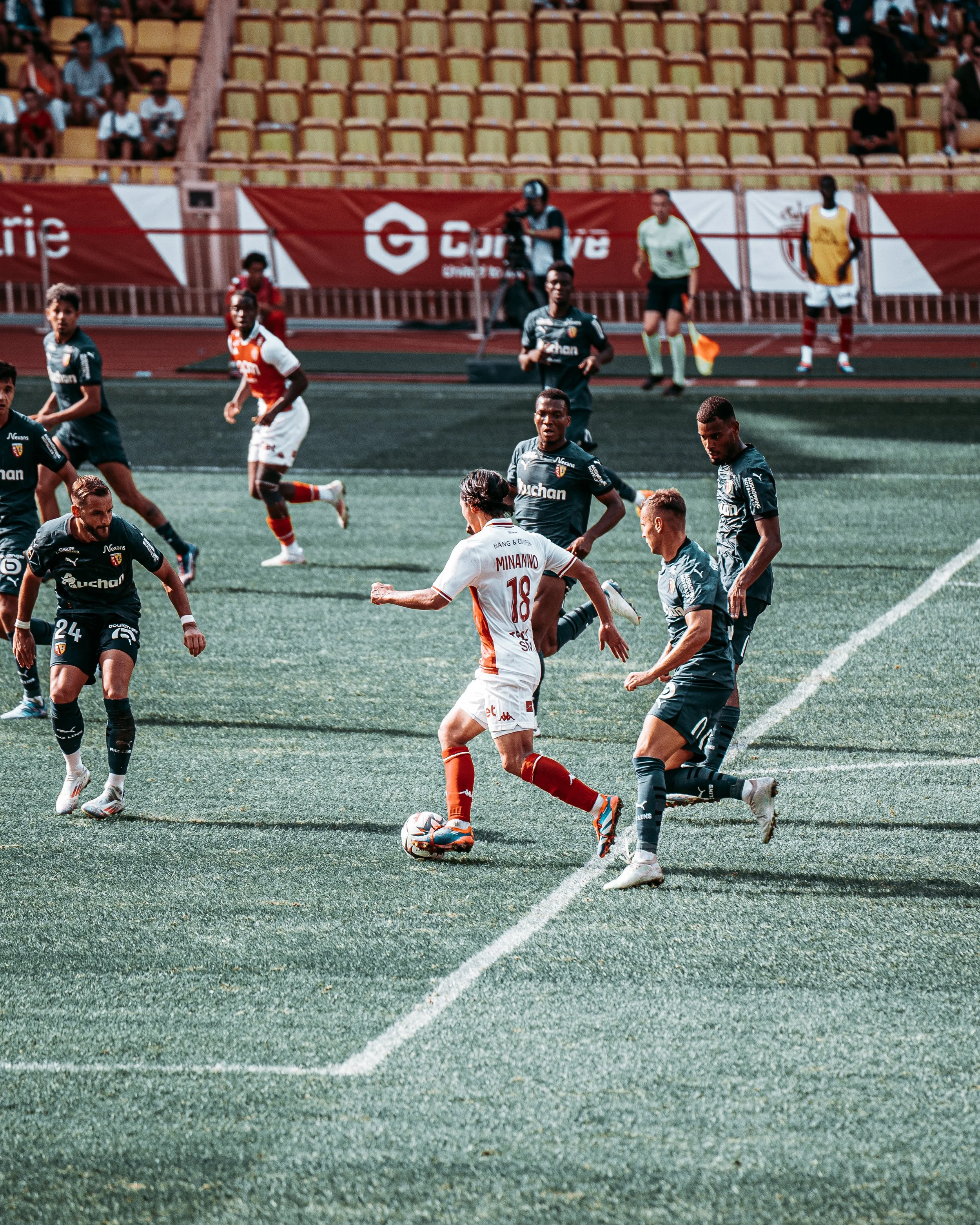Footballeurs en action sur le terrain lors d'un match avec des spectateurs dans les gradins.