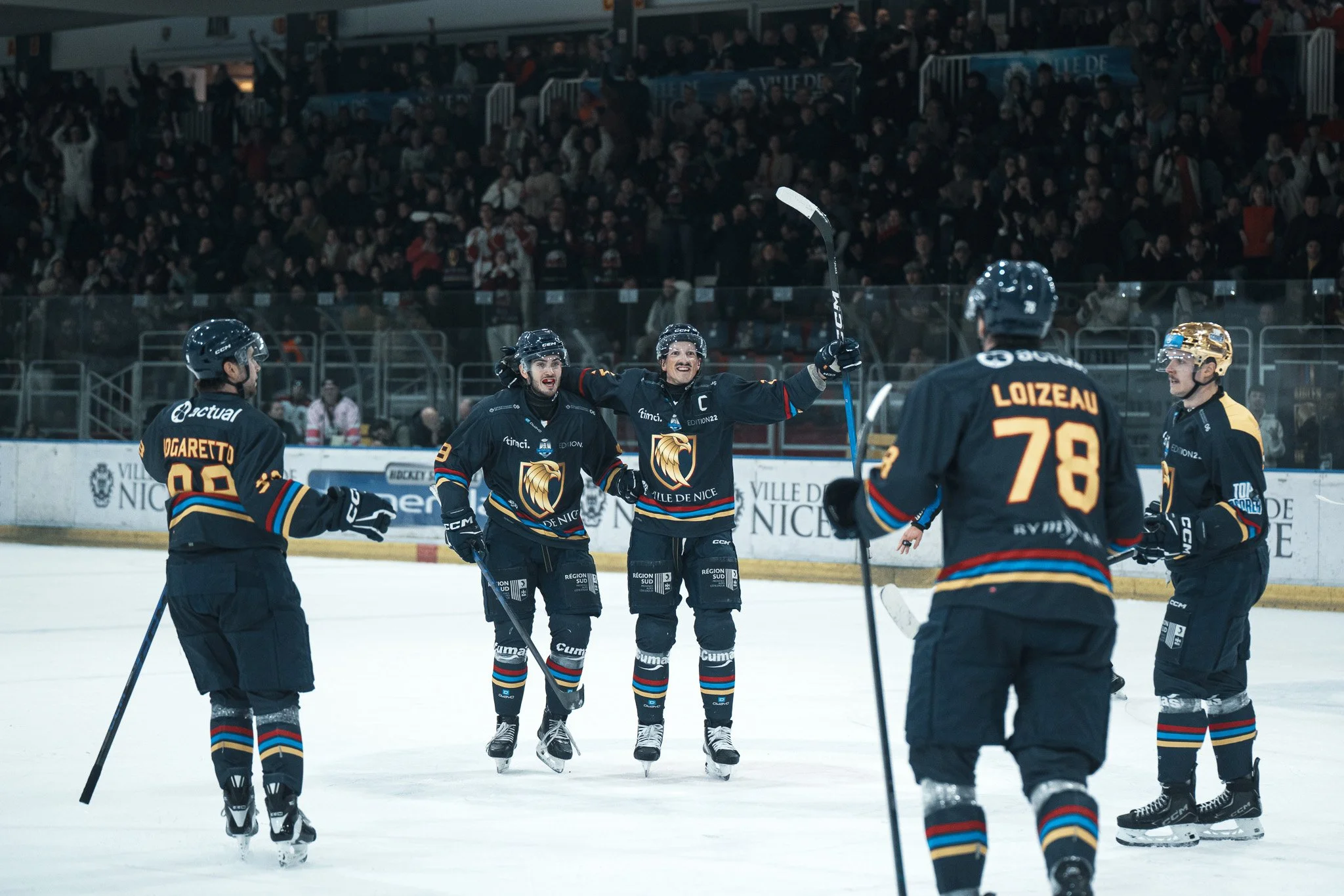 Joueur de hockey de l'équipe de Nice célébrant un but avec ses coéquipiers sur la glace, pendant un match.