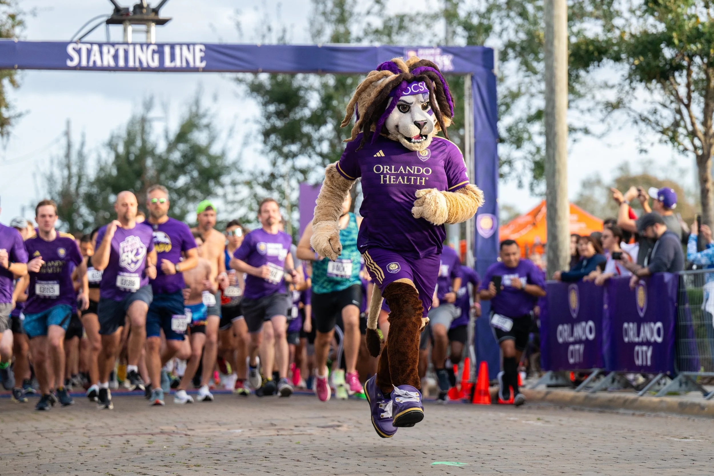 Kingston the mascot is starting the 5K running race in front of a crowd of people