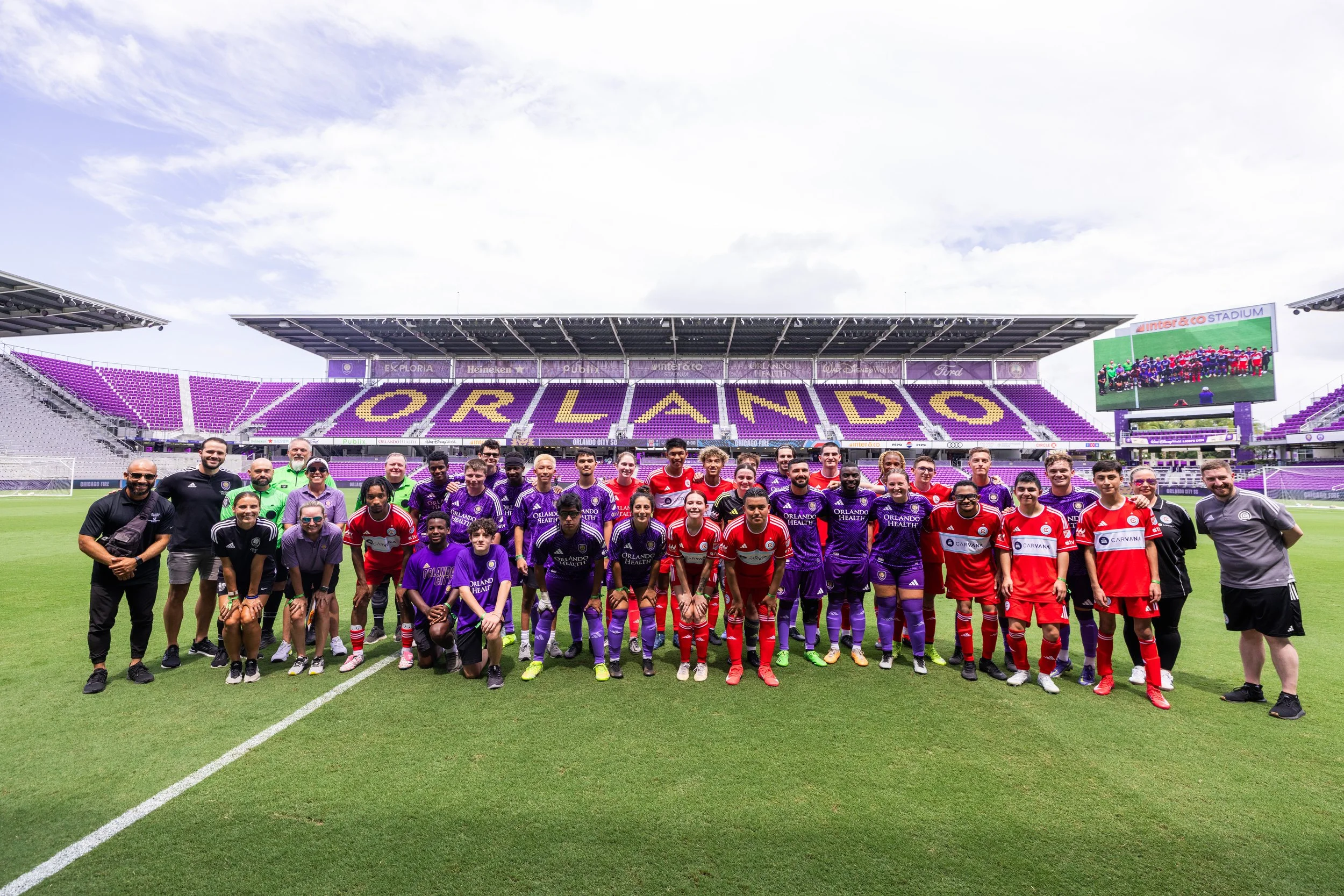 two teams of Special Olympics Unified athletes and partners standing together on the grass field at Inter&Co Stadium after playing a match together