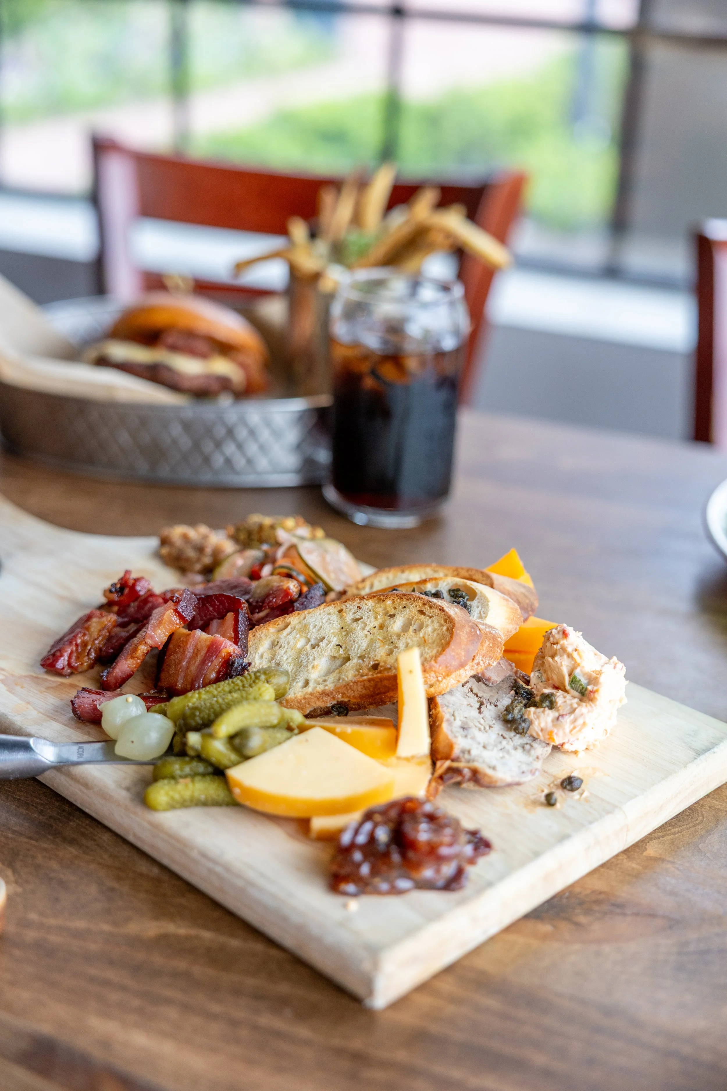 Assorted charcuterie board with cheeses, meats, crackers, and garnishes on a wooden serving board.