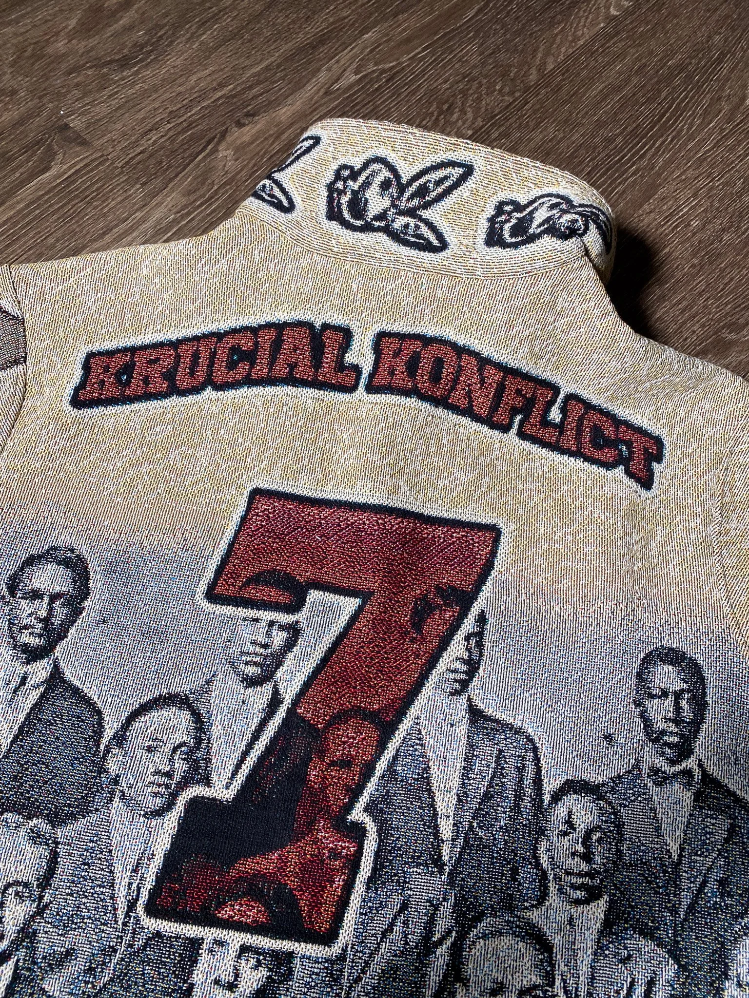 Close-up of a vintage racing patch featuring the number 7, the word 'RUGGLRL KONNECTION', and several skull and dog illustrations, stitched onto a fabric surface.