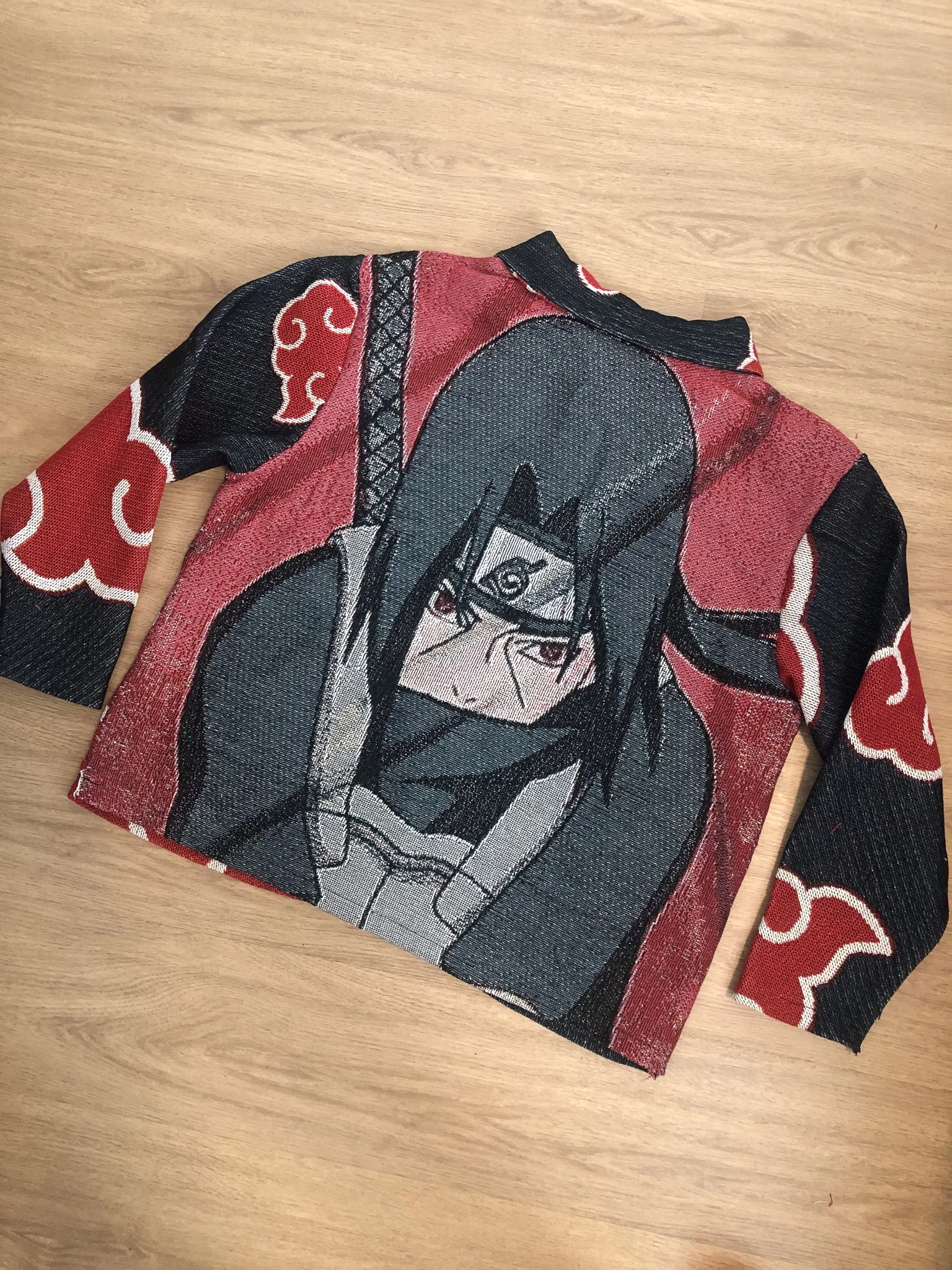 A piece of fabric clothing featuring a graphic of a female character with glasses and long hair, set against a red and black background with white details.