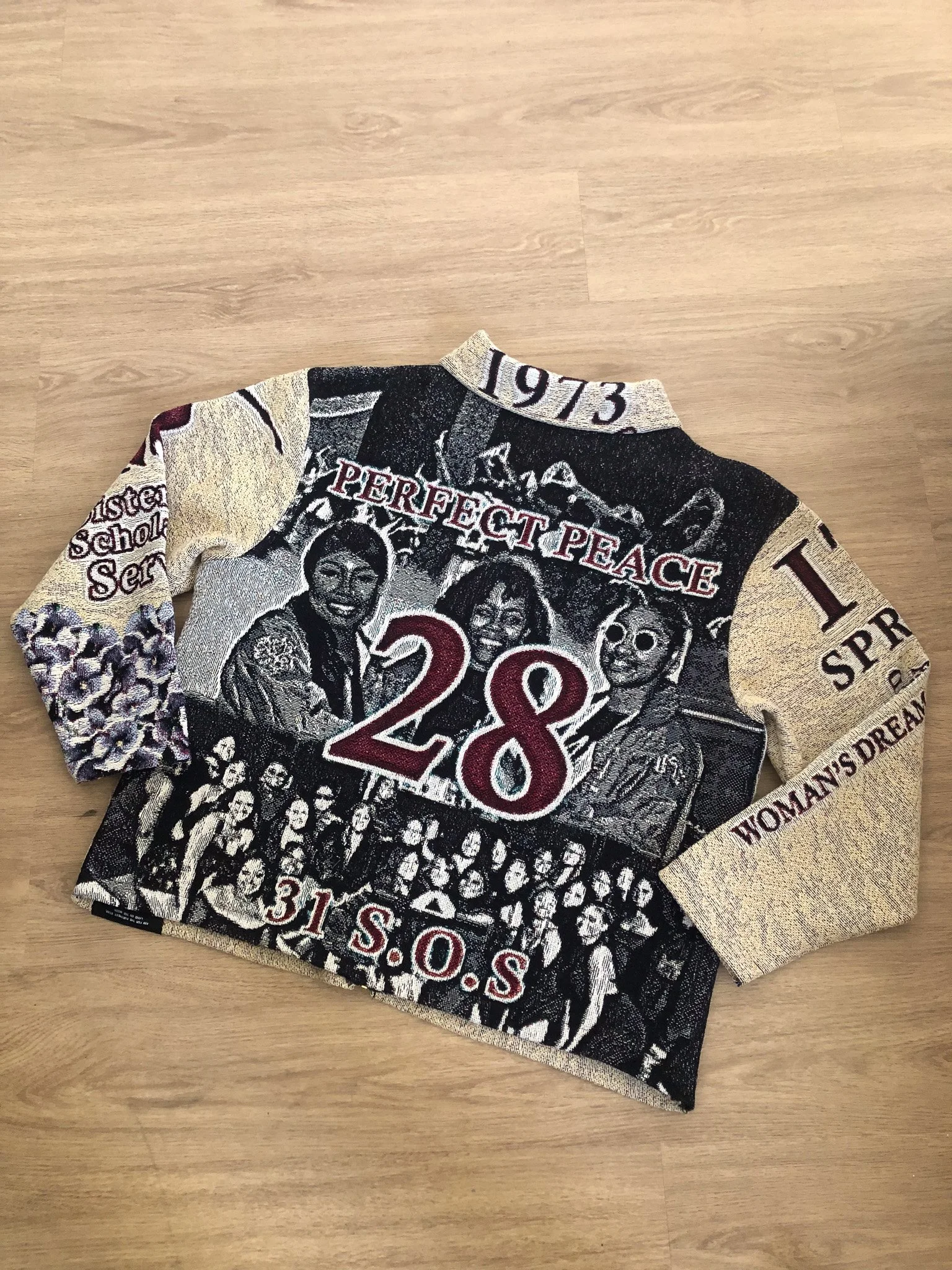 Part of a printed fabric shirt featuring a black and white image of women, the words 'PERFECT PEACE' and the number '28' in red, and various decorative elements.