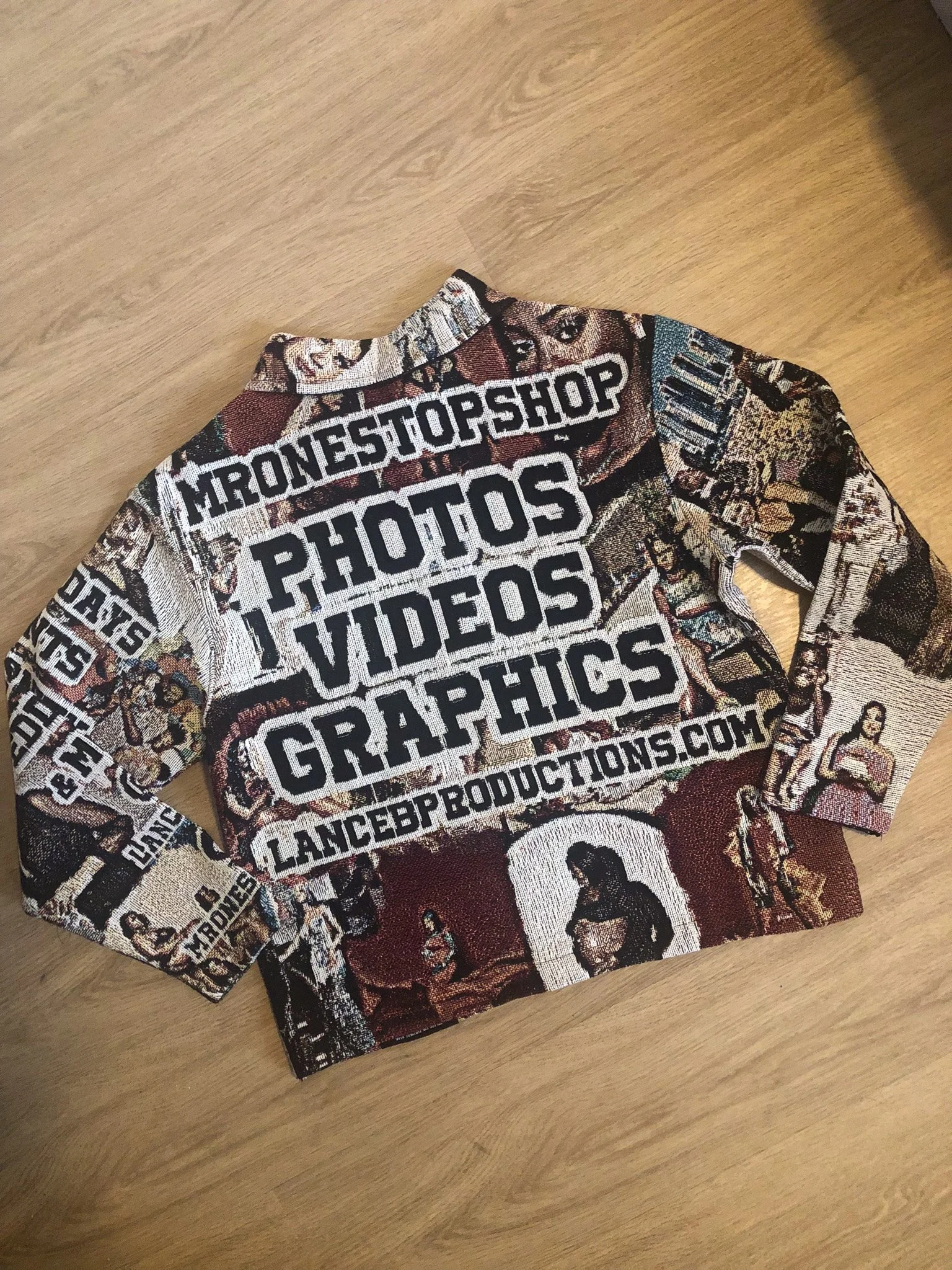 Close-up of a multicolored, patterned fabric shirt with text and images, laid on a wooden surface.