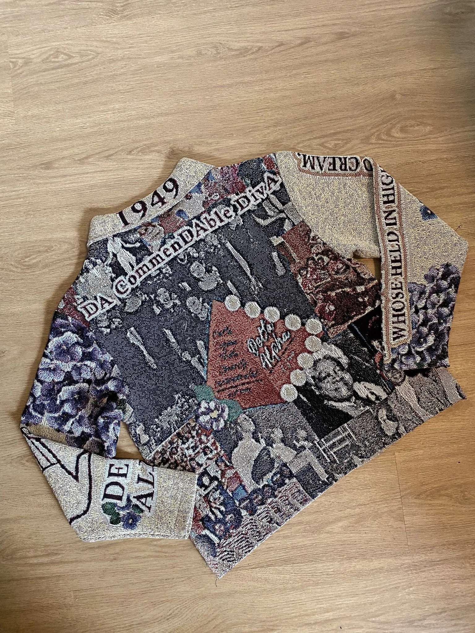 A piece of fabric with a intricate pattern and text, lying on a wooden surface.
