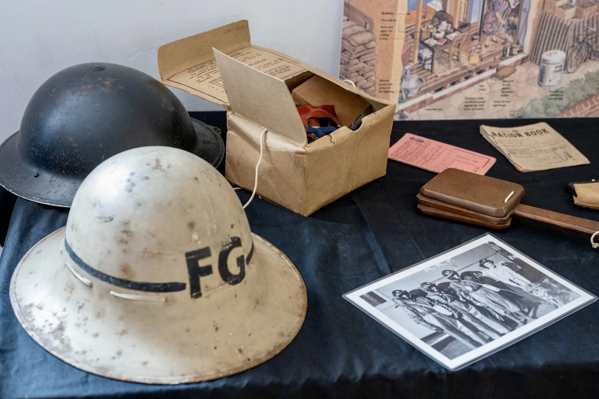 A display of vintage military helmets, old photographs, and wartime memorabilia on a black table.