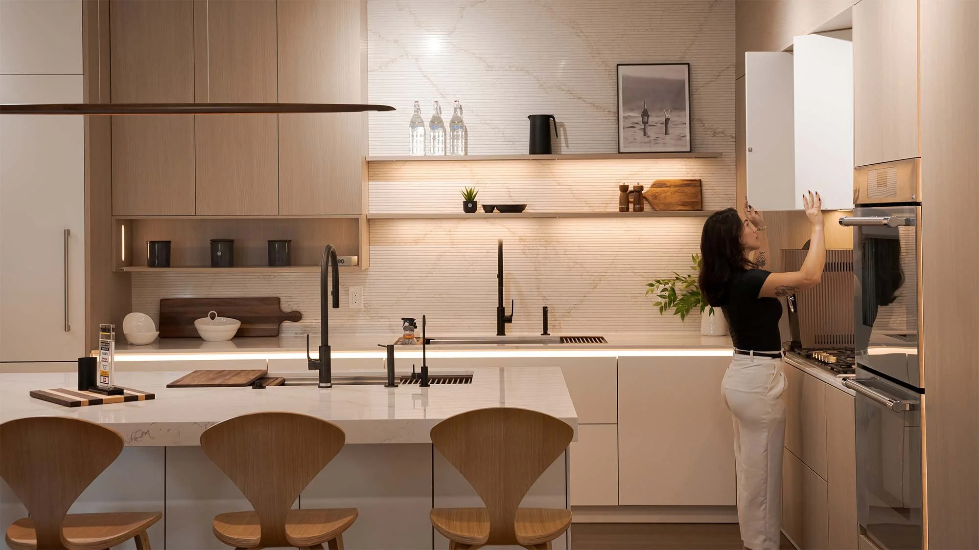 A couple sitting at a kitchen island table, smiling and enjoying each other's company in a modern kitchen with wooden cabinets and decorative vases.