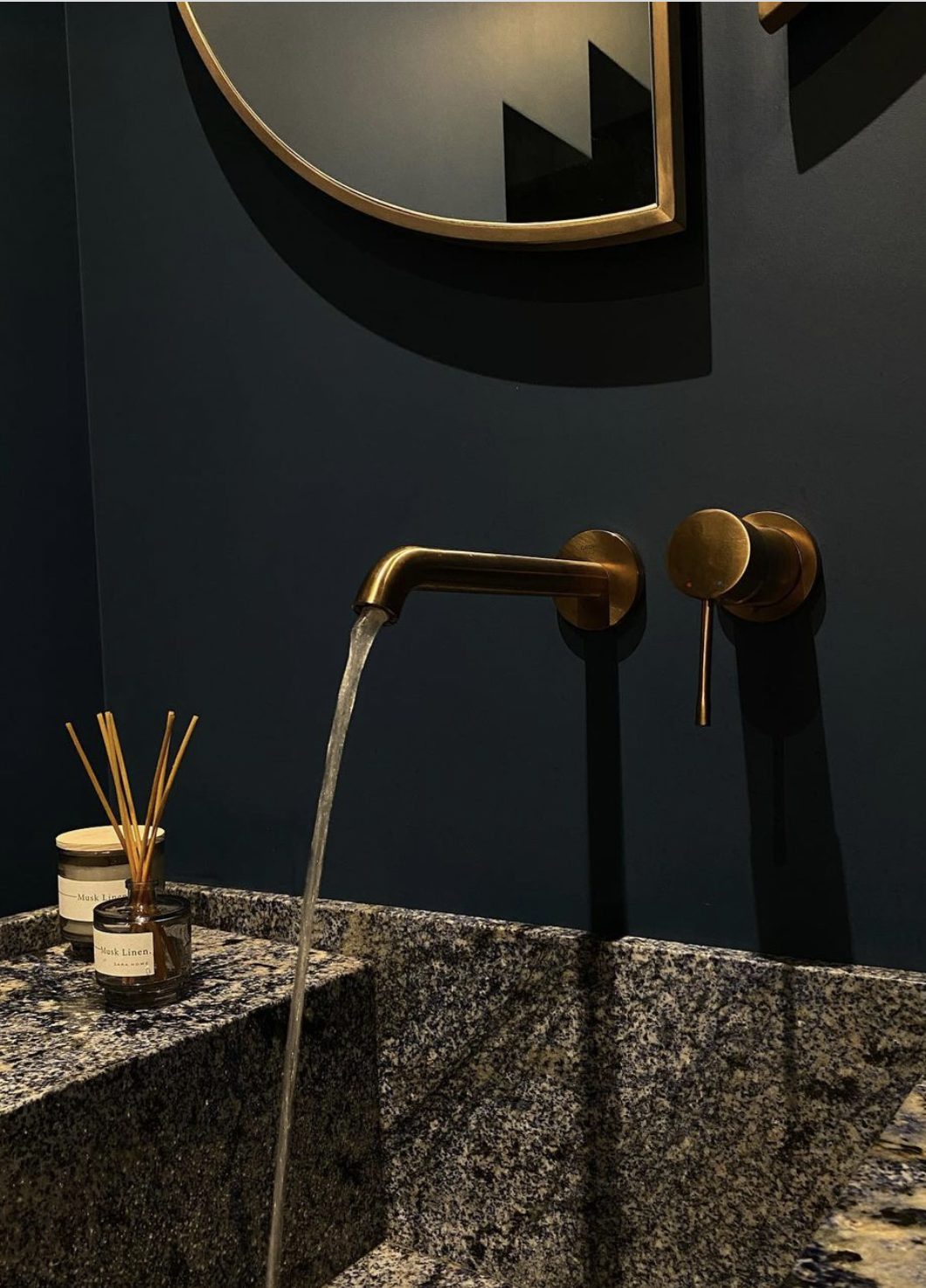 modern luxury bathroom with dark blue wall, granite countertop and brass accessories