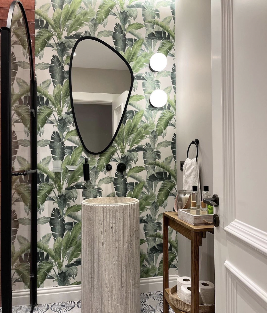 Elegant bathroom with mediterranean style cinnamon red wall tiles and blue white floor tiles, and tropical leaves design wallpaper.