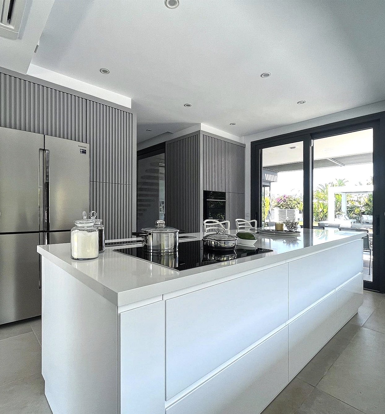 In the heart of the modern minimalist kitchen stands the central island, adorned with the same sleek gray-toned quartz countertop, the island becomes a versatile workspace.