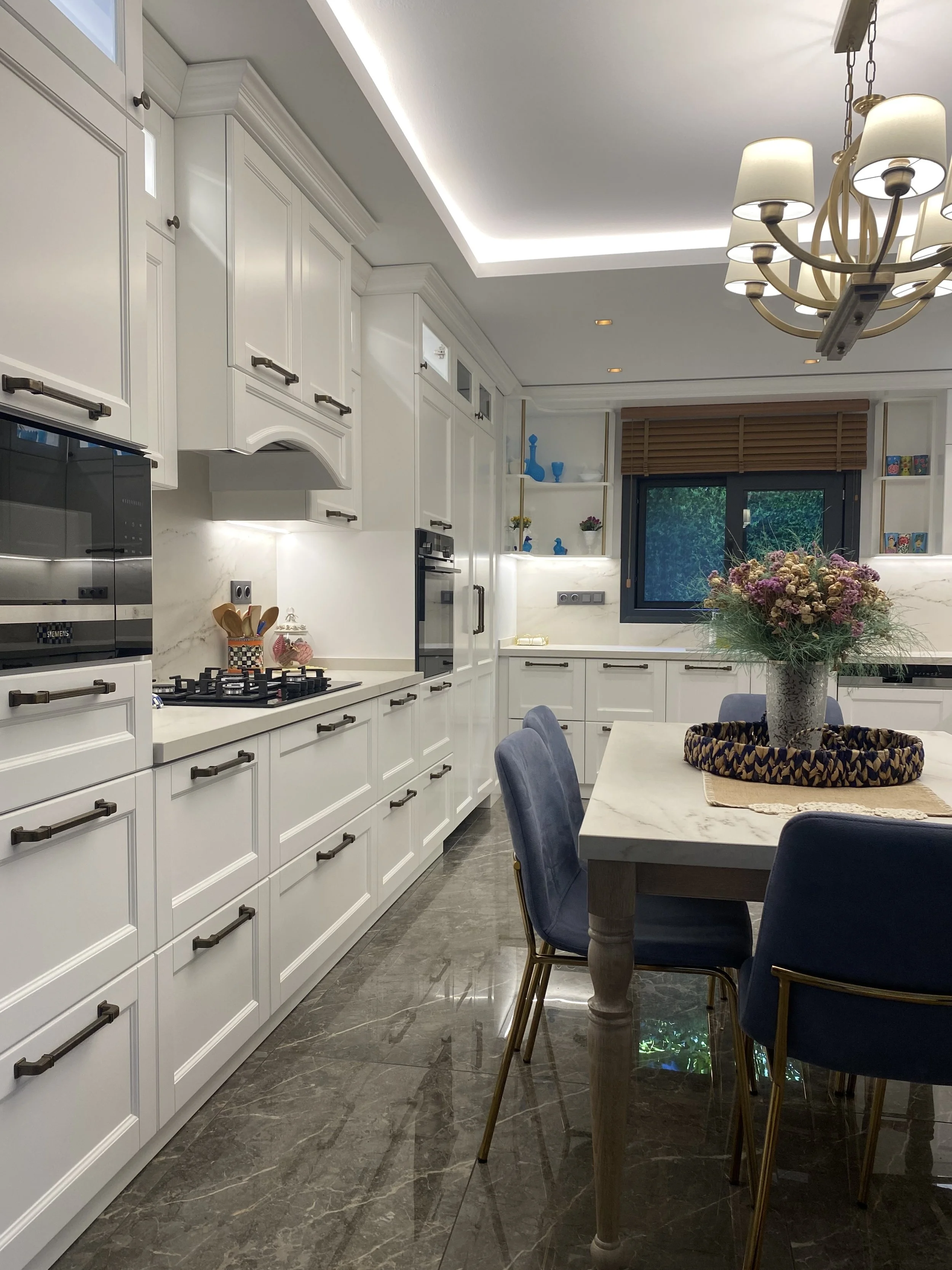 Bright open-concept kitchen featuring traditional shaker cabinetry and a central custom dining table with matching stone top.