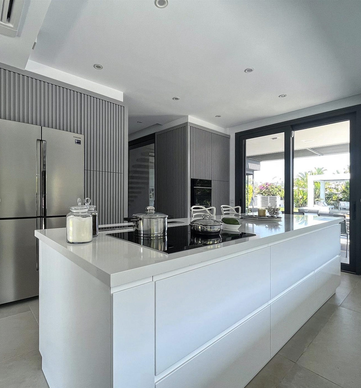 Ultra-modern fluted kitchen with custom vertical slatted cabinet doors, integrated appliances and a bright white island, crafted by Nuovo Kitchens in Vancouver.